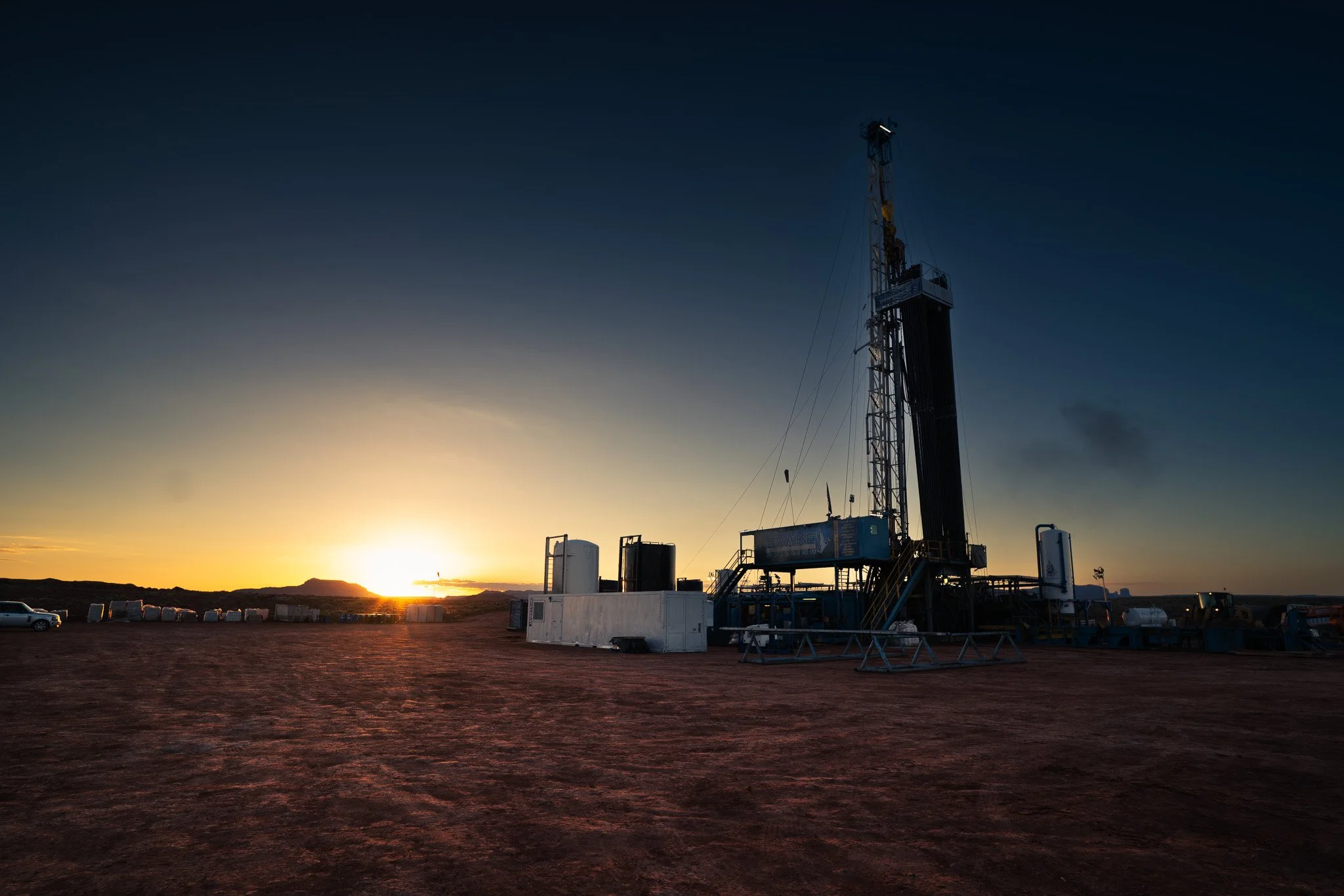 A potash well on a flat, barren landscape during sunset with a darkening sky.