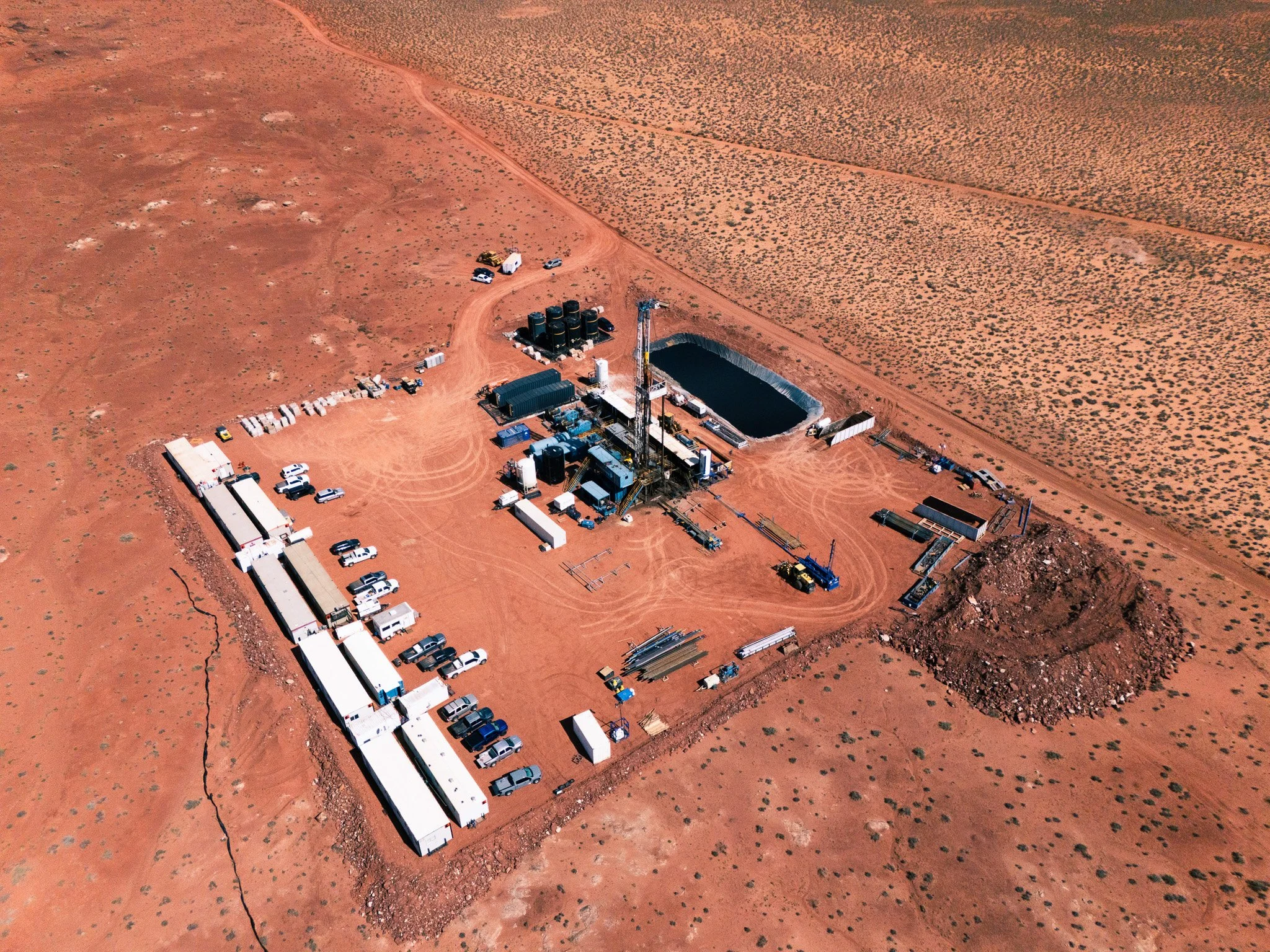  aerial view of a potash drill site in a desert landscape with equipment, vehicles, tanks, and temporary structures.
