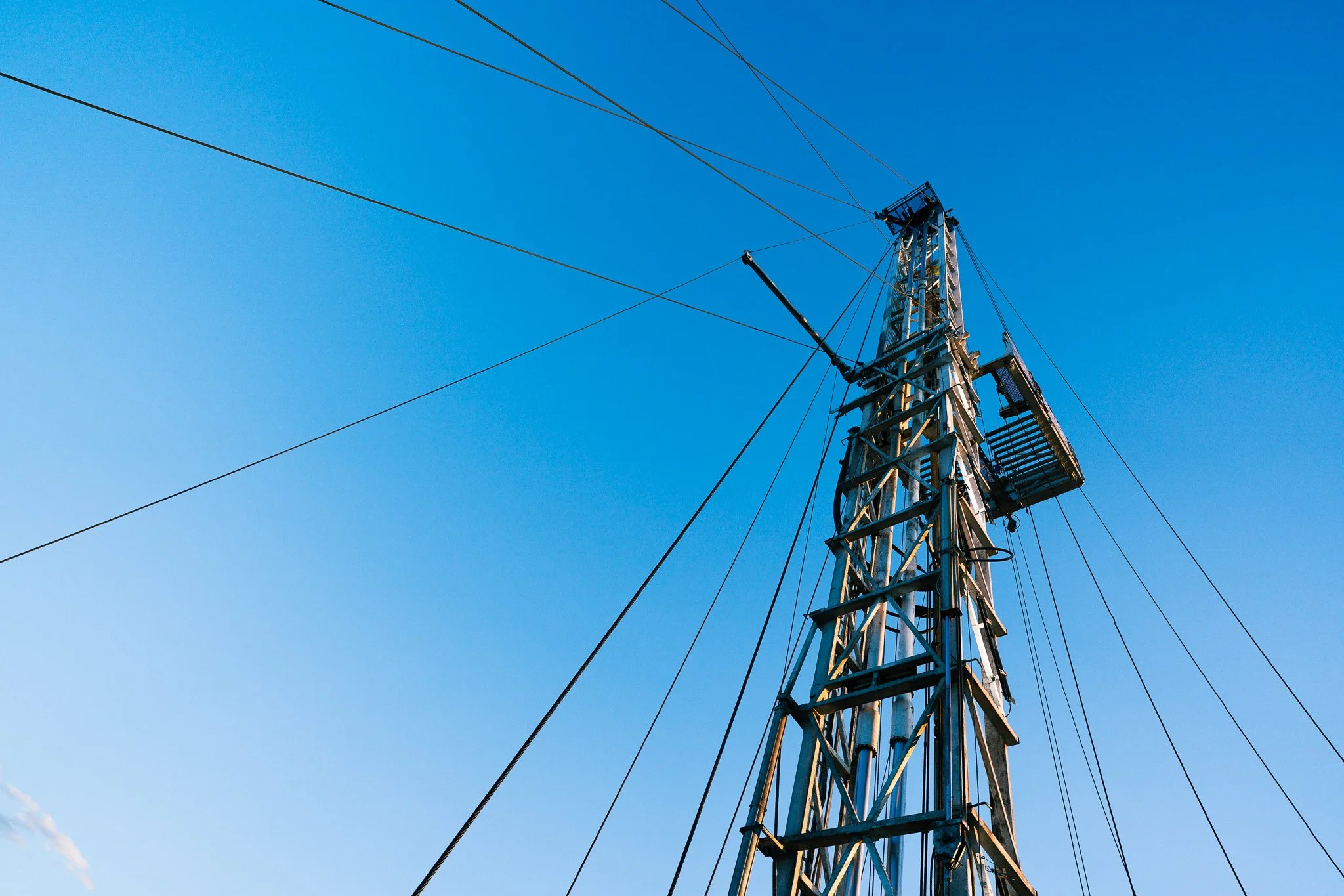 View of a tall telecommunications tower with multiple antennas and metal framework against a clear blue sky.