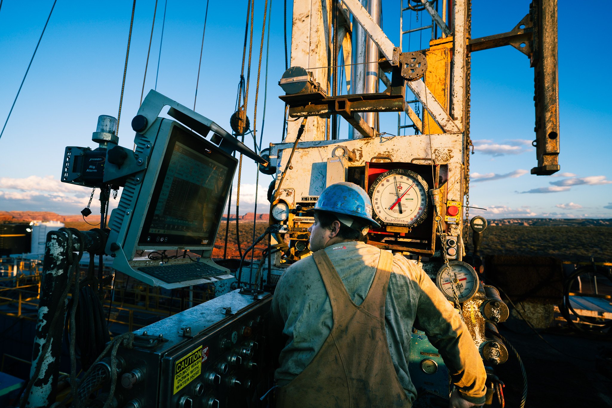Workers operating machinery on a potash well during sunset, with a clear sky in the background.