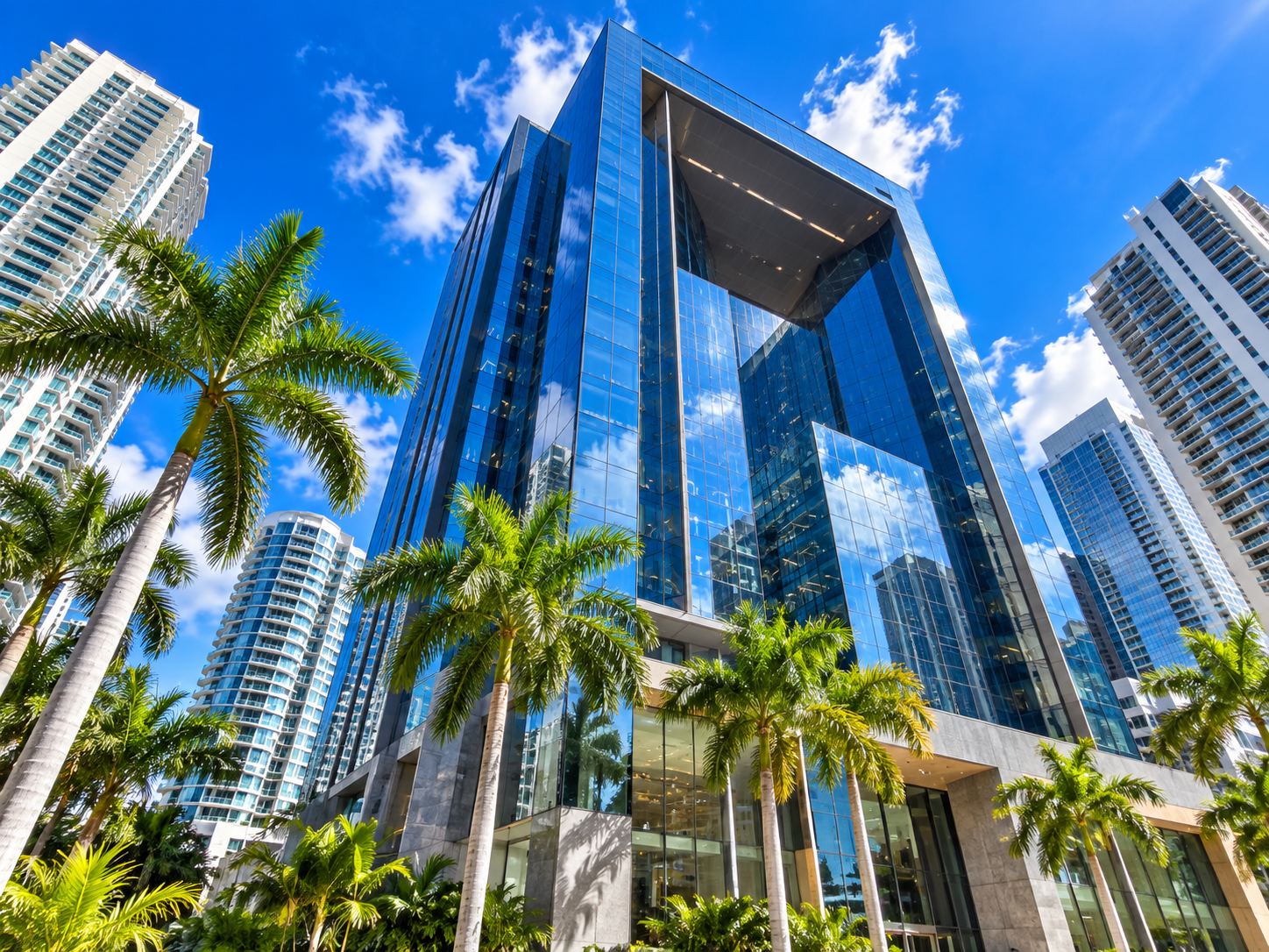 Modern high-rise office building with glass exterior and palm trees in an urban business district.