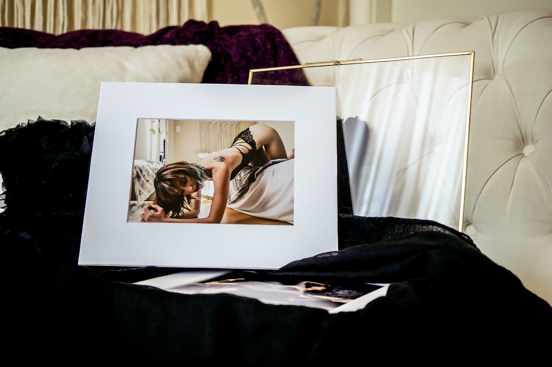 Framed photograph of a person posing on a sofa, displayed on a white cushion with a black scarf.
