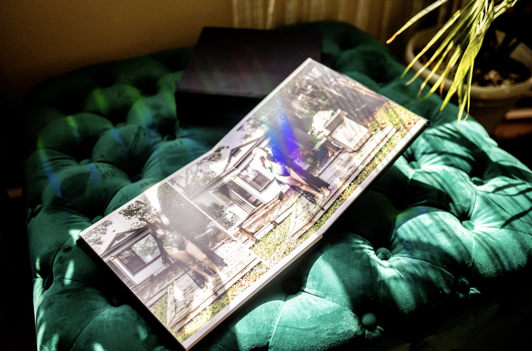 Photo album displayed on green velvet ottoman with sunlight.