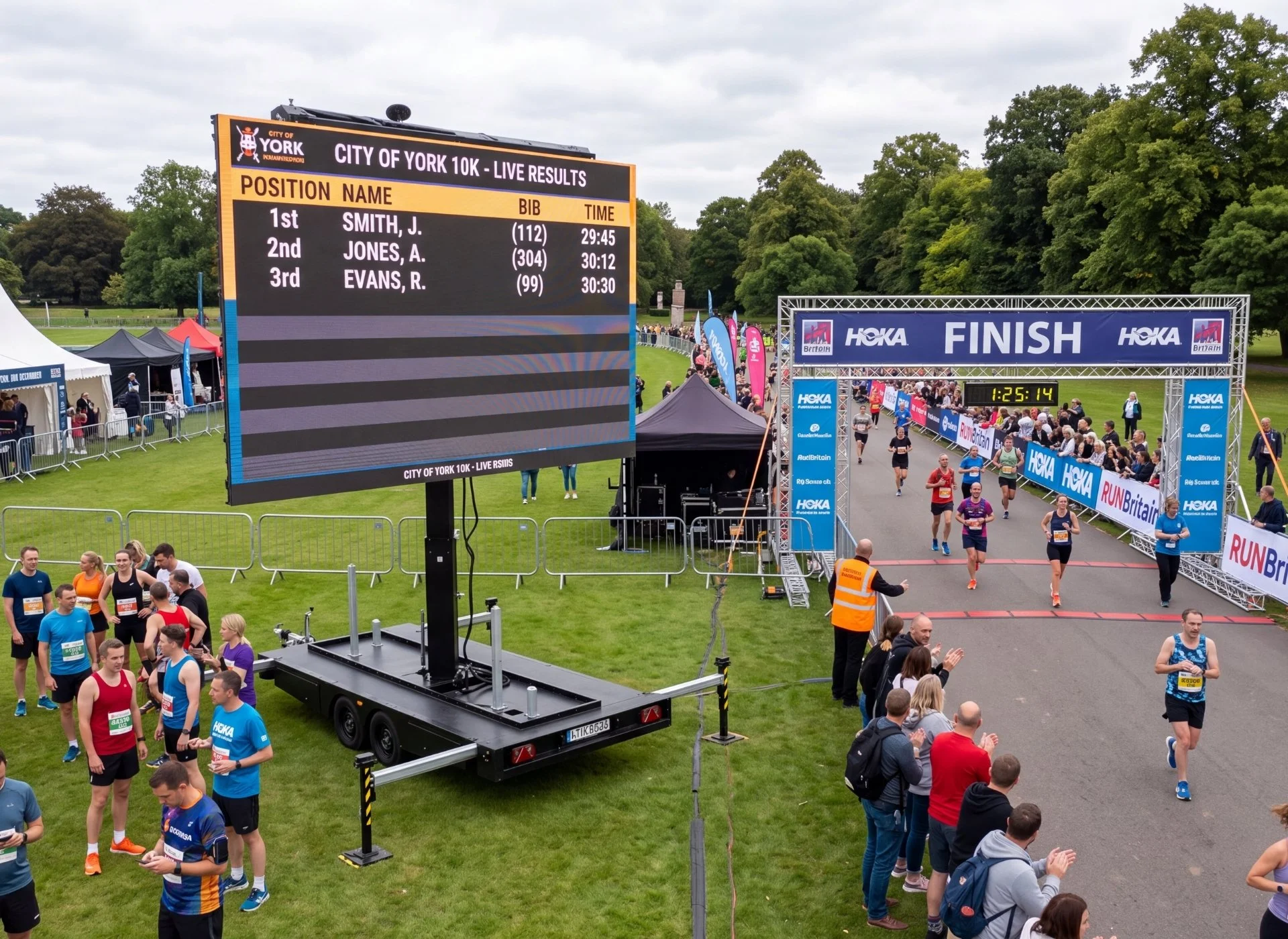 Runners participating in a marathon race crossing the finish line, with a large electronic scoreboard displaying results and a crowd of spectators and supporters on either side.