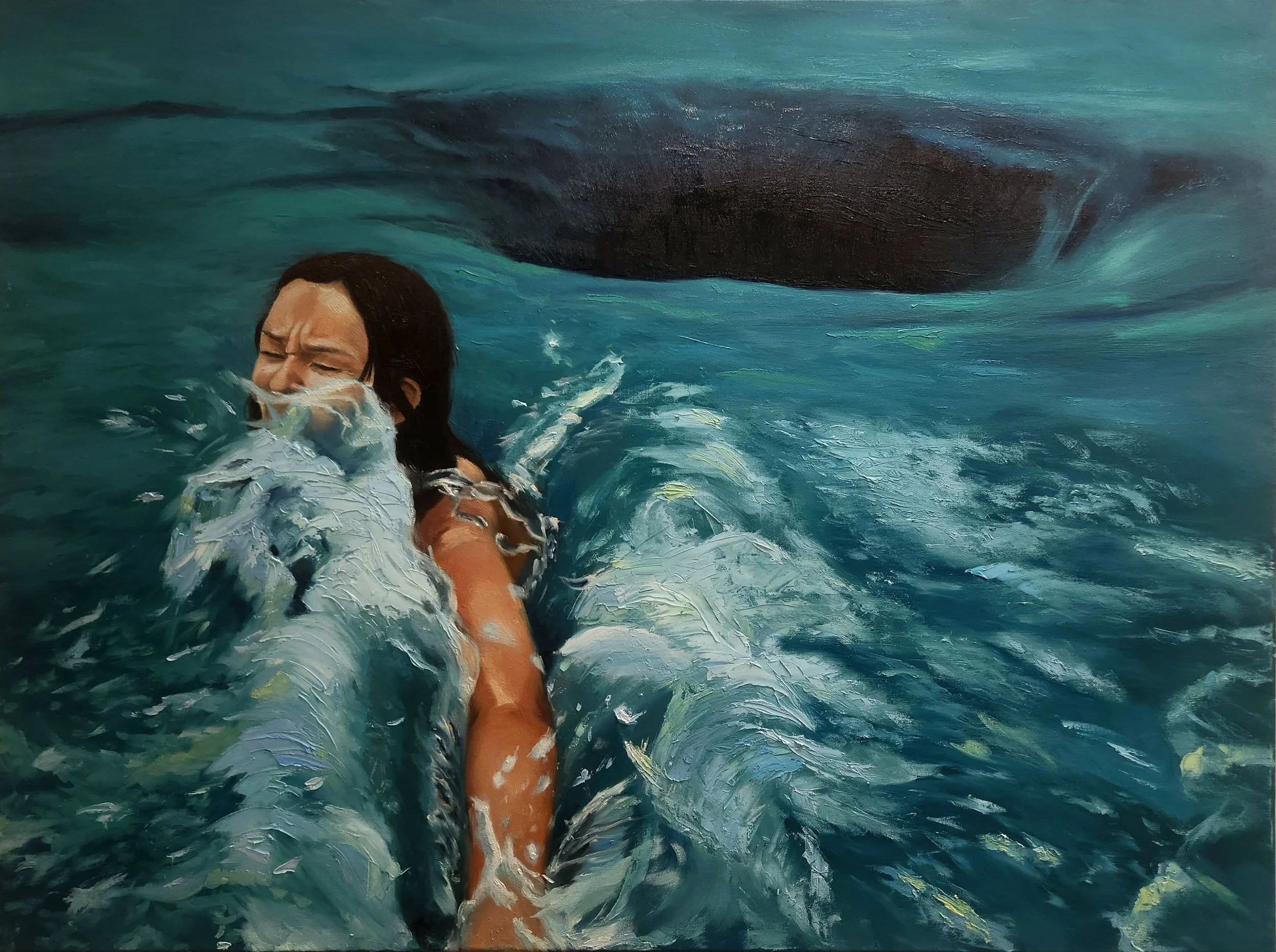 A person with long dark hair and tanned skin is swimming in the ocean, with their eyes shut and face partially submerged in the water. A large dark whale is visible beneath the surface of the water in the background.