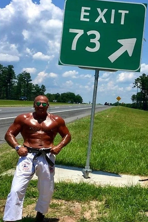 Nabil at age 73 beside an Exit 73 highway sign