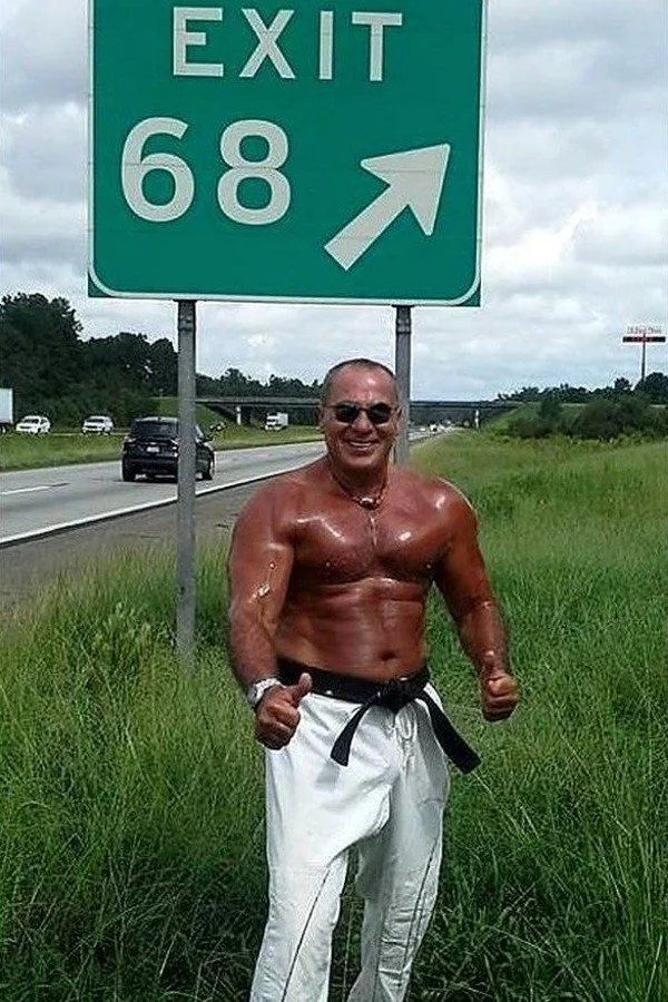 Nabil at age 68 beside an Exit 68 highway sign
