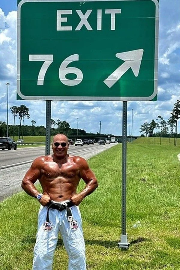 Nabil at age 76 beside an Exit 76 highway sign