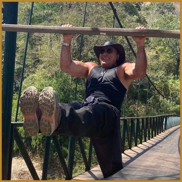 Nabil doing a hanging leg raise from the rail of a footbridge in Cochin, India, 2020