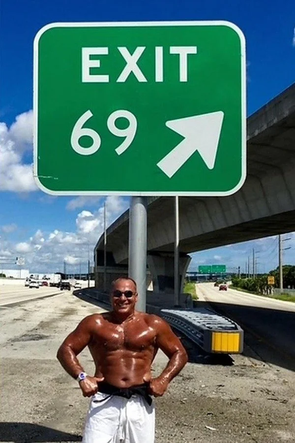 Nabil at age 69 beside an Exit 69 highway sign