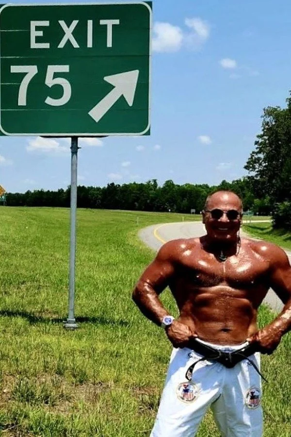Nabil at age 75 beside an Exit 75 highway sign
