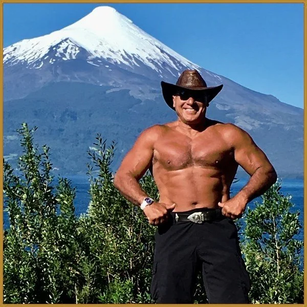 Nabil in a cowboy hat, shirtless, in front of a lake and a snow-capped volcano near Puerto Varas, Chile, 2016