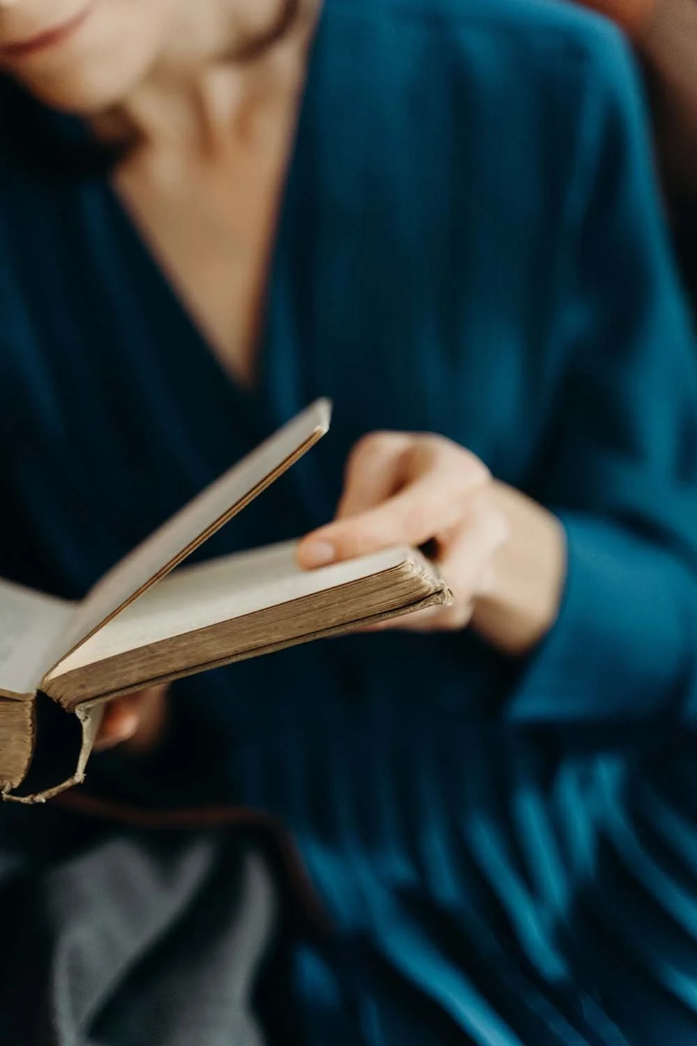 Person writing in a journal while seated in a blue dress.