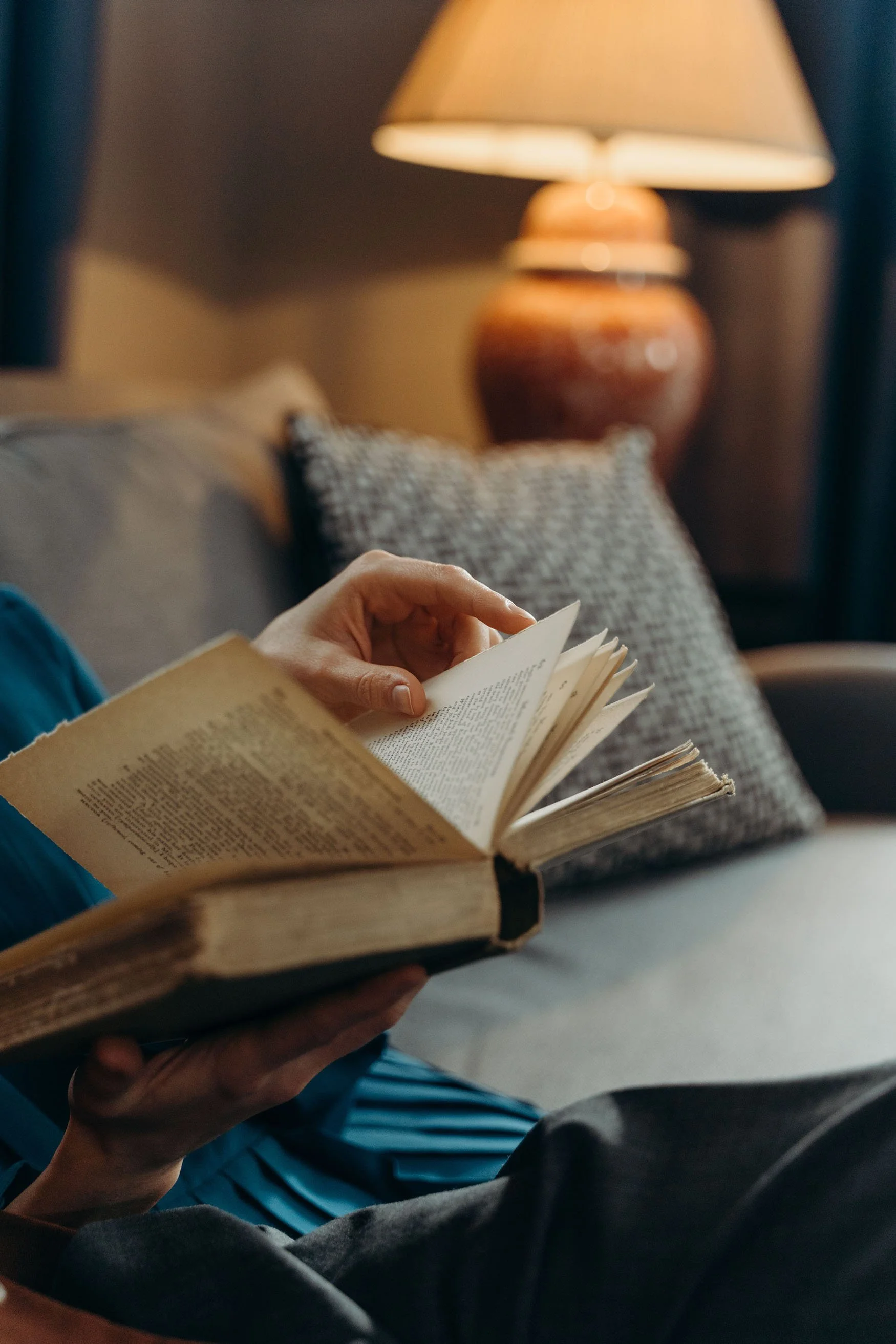 Person reading a book in a cozy chair.