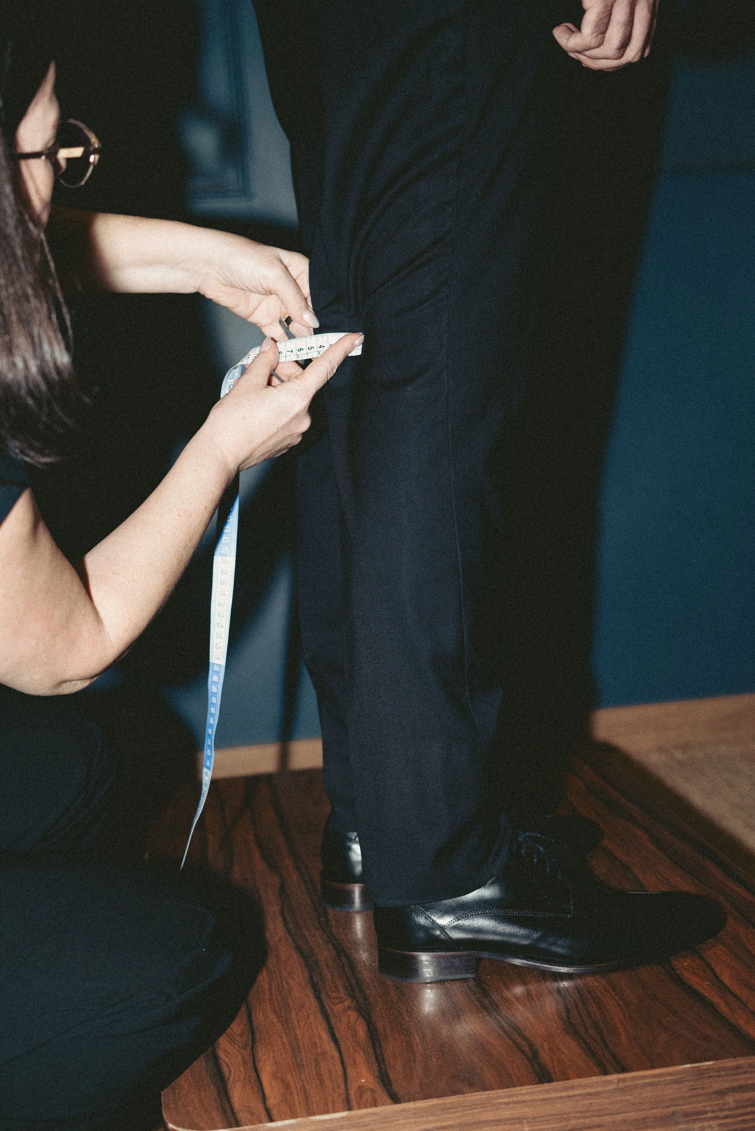 Person measuring another person's waist with a measuring tape at an indoor event.