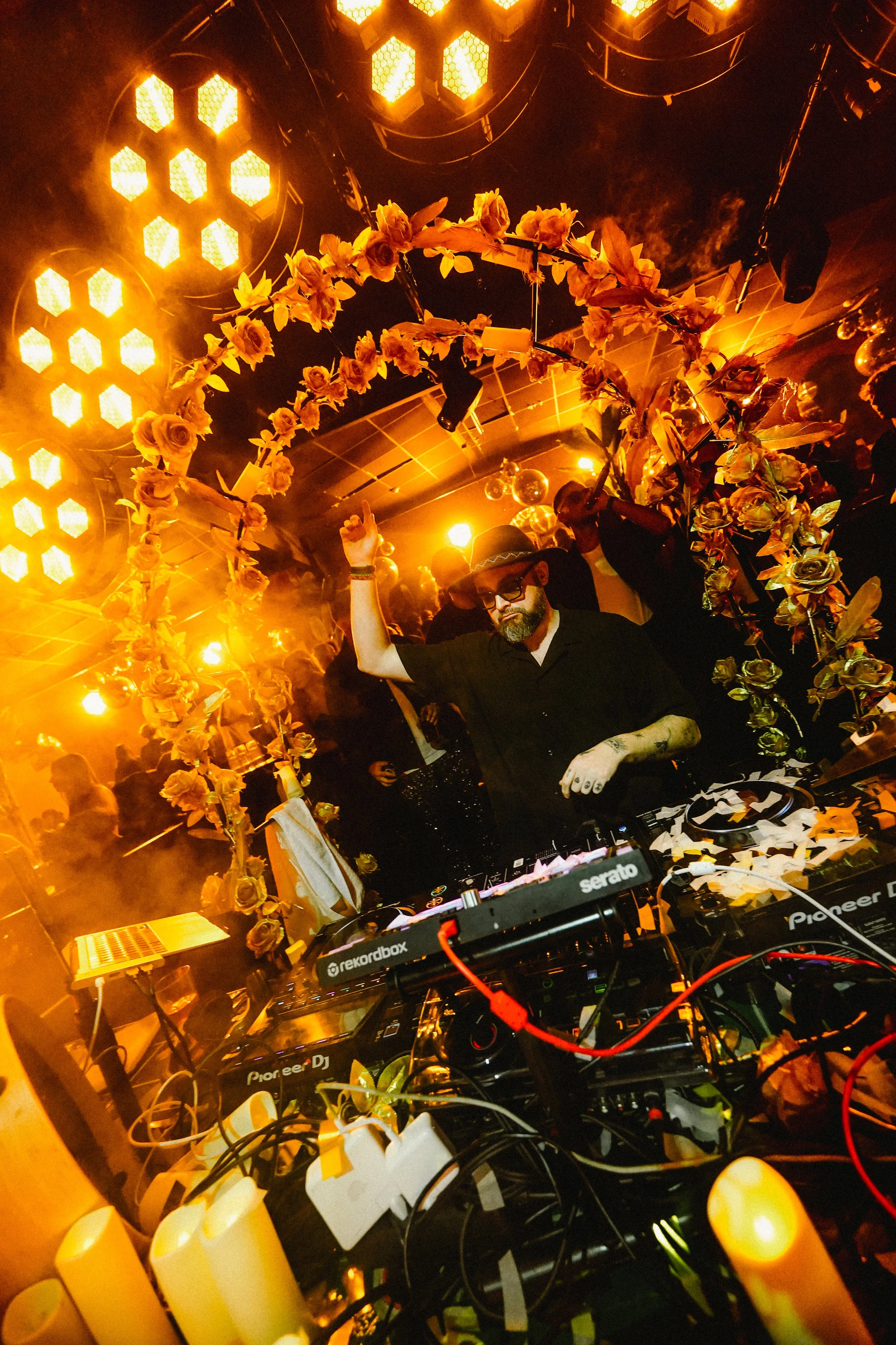 DJ playing music at a party with yellow floral decorations and warm lighting.