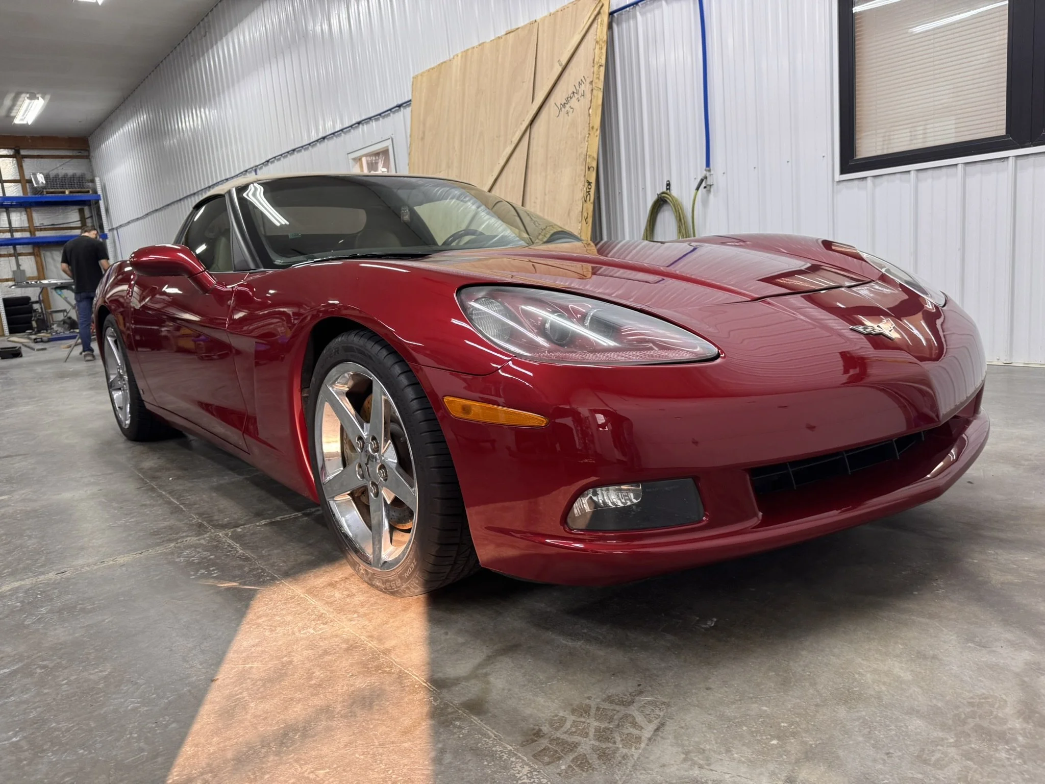 A red Chevrolet Corvette sports car parked inside a warehouse or garage.