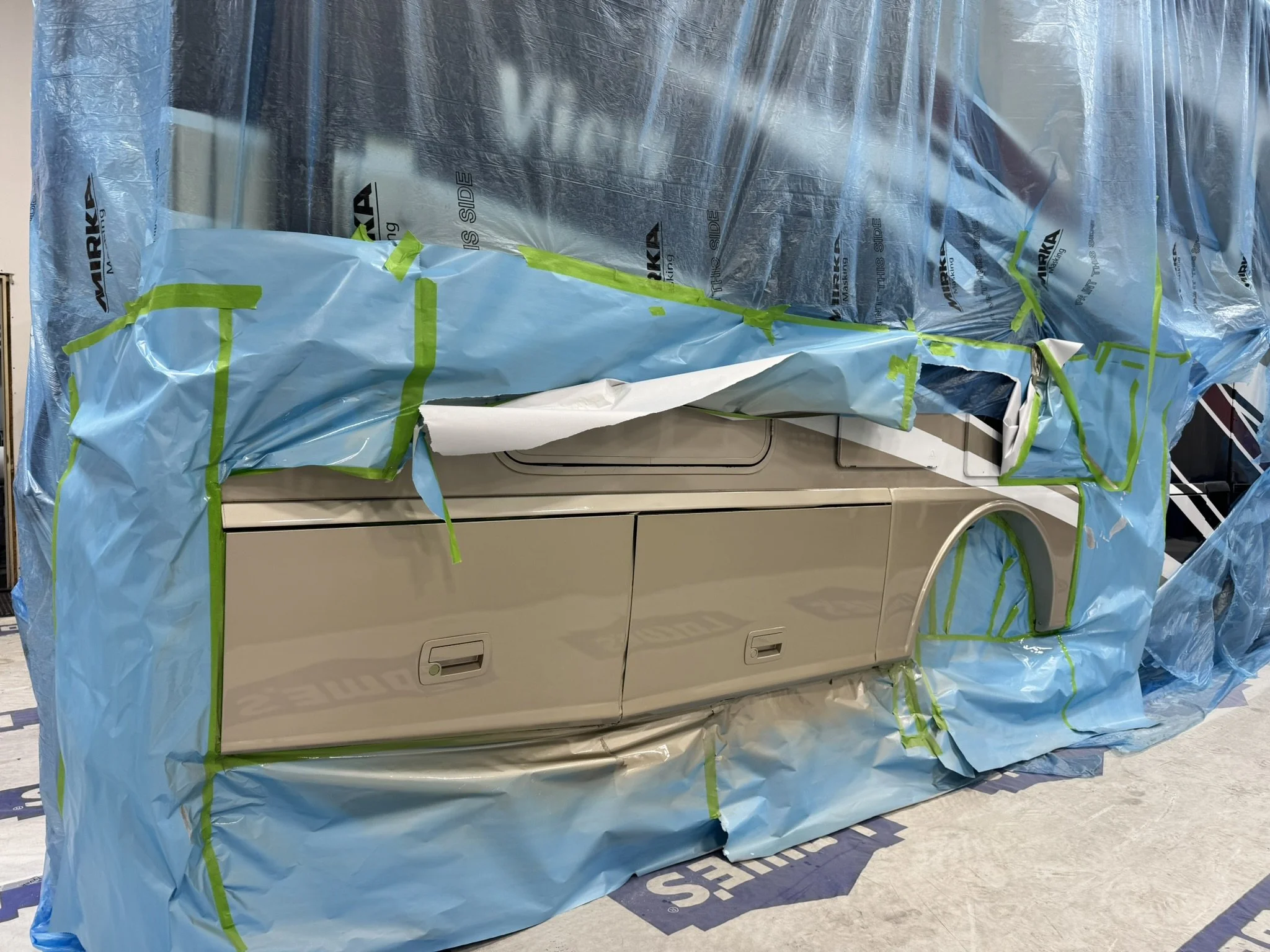 A washing machine covered with blue and green protective plastic and tape.