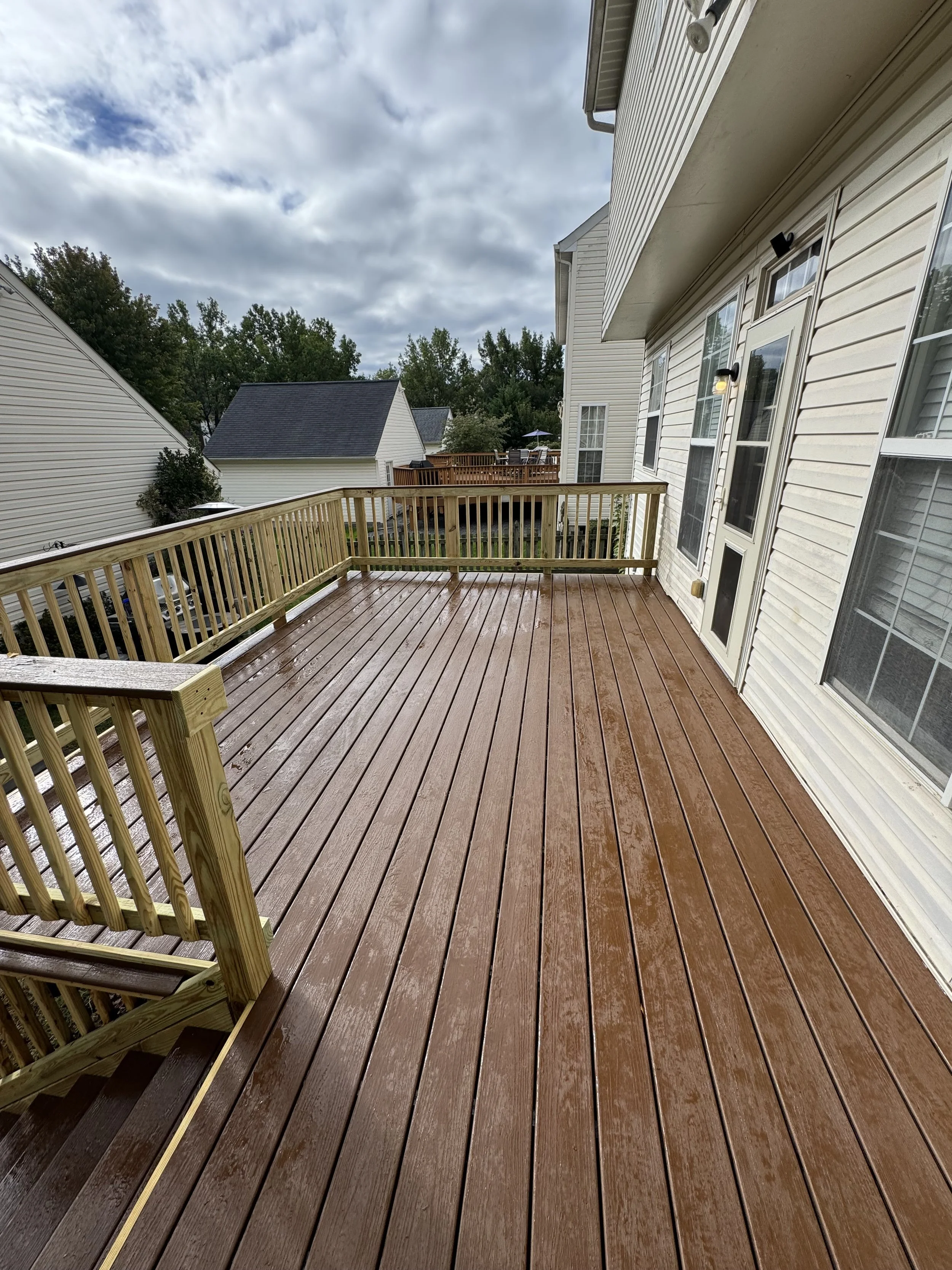 Dry wooden deck on a residential balcony with a white house exterior and sliding glass door