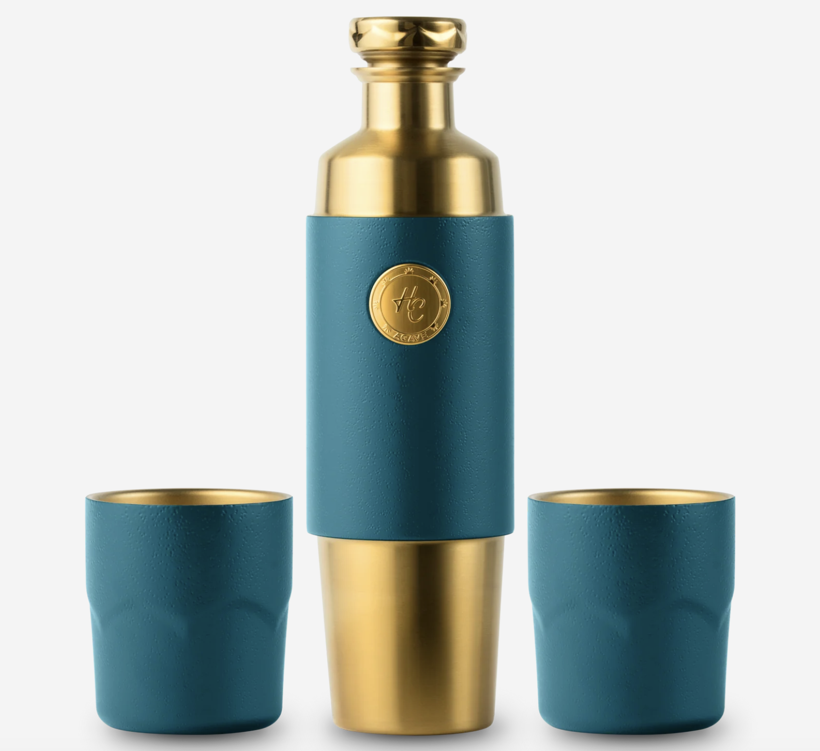 A teal and gold thermos with a textured teal body, a gold collar, and a gold emblem on the front, accompanied by two matching teal cups with gold rims, all against a white background.