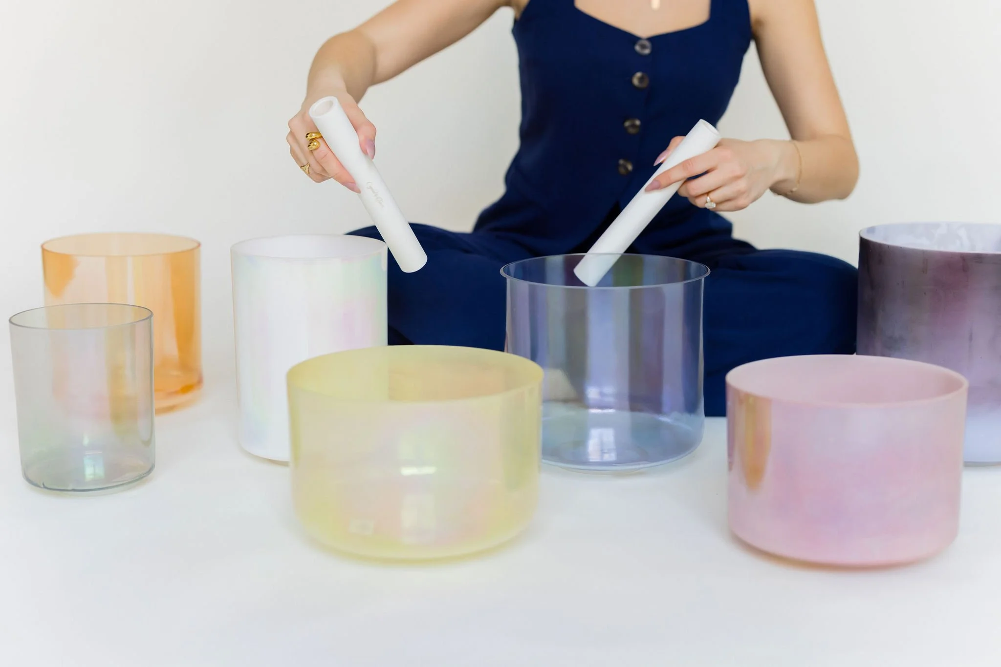 Crystal Tones Alchemy Bowls arranged on a table, with Lindsay demonstrating mallets.