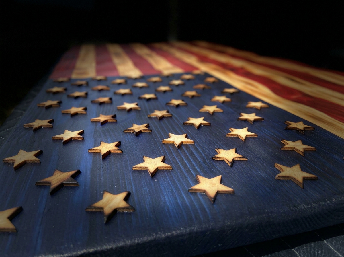 Wooden stars arranged on a wooden surface painted with the American flag's red and white stripes and blue field with stars.