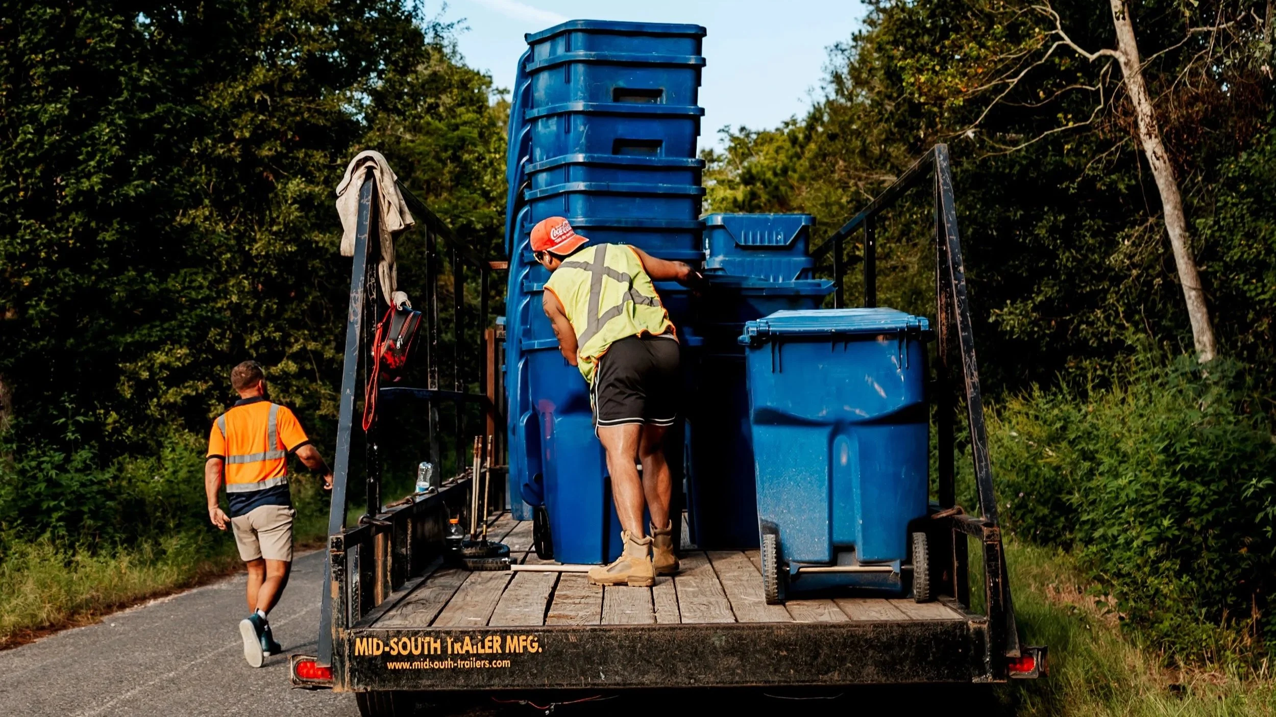 OnlyCans crew unloading blue residential carts from a trailer