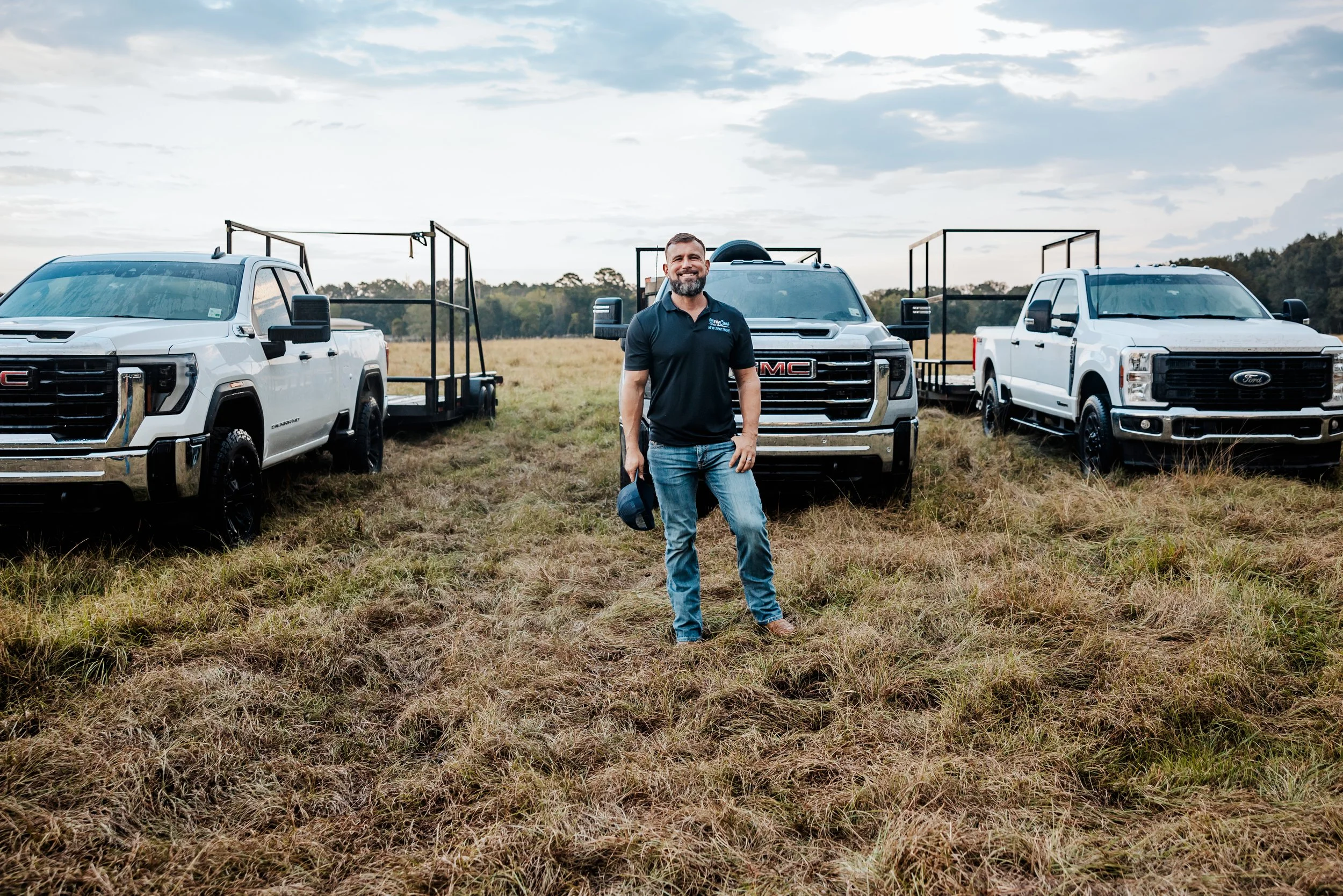 OnlyCans owner standing with company trucks and trailers