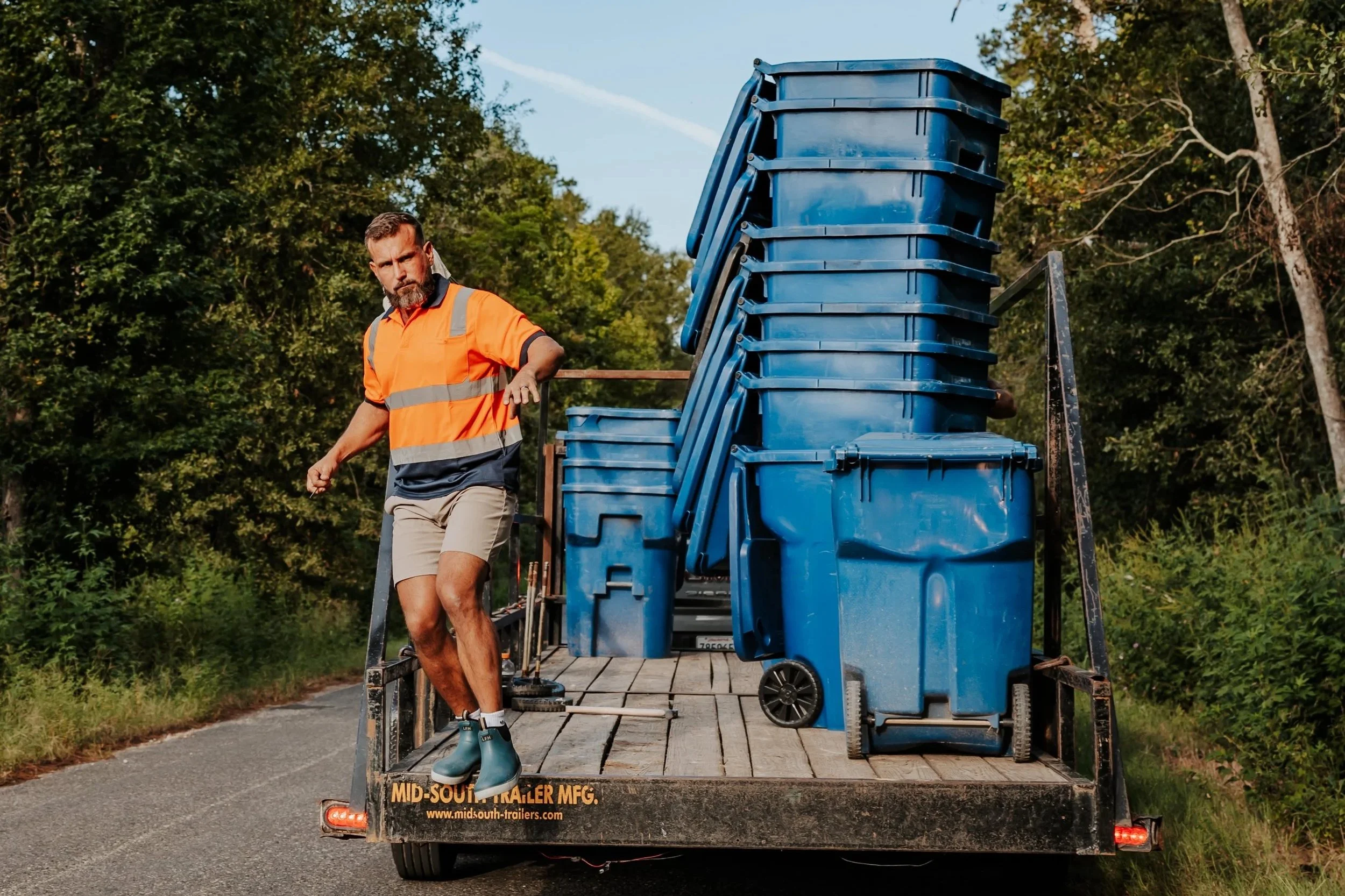 OnlyCans worker transporting blue residential carts on a trailer