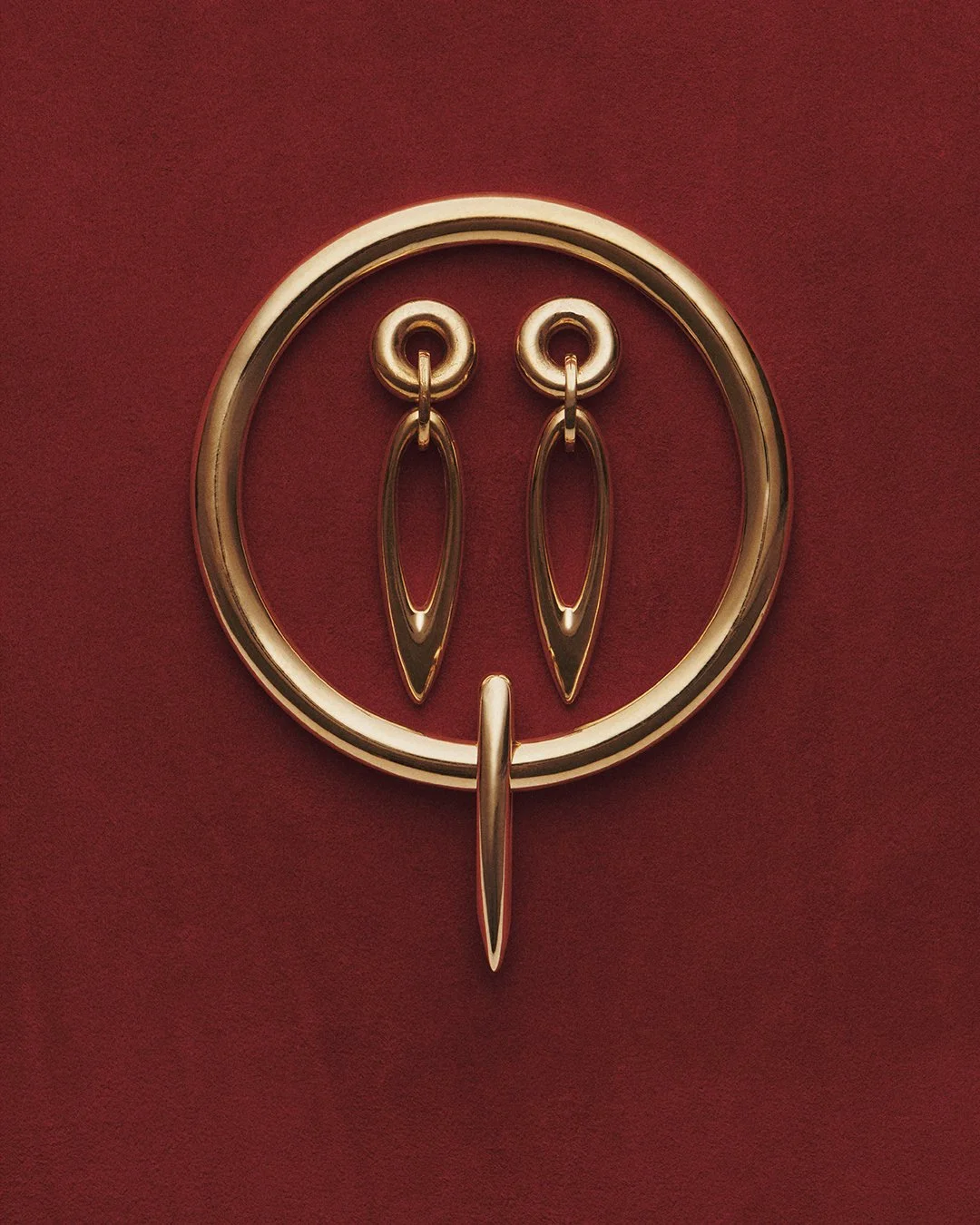 Gold earrings hanging on a decorative gold ring display against a red background.