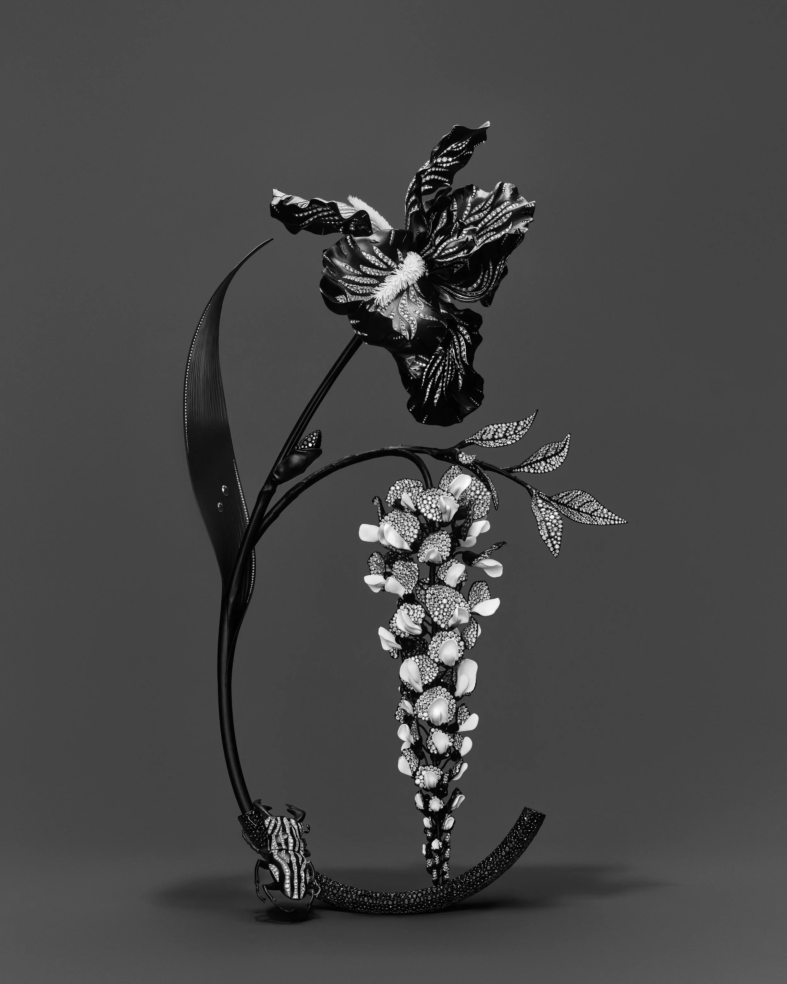 A black and white sculpture of a frog, with intricate patterns and embellishments, attached to a long, decorated tail, against a plain background.