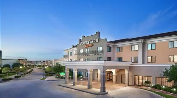Courtyard by Marriott hotel exterior at dusk with a clear blue sky, well-lit entrance, and landscaped surroundings.