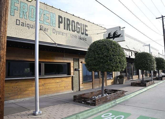 Street view of a restaurant named Frozen Pirogue with wooden exterior, large trees in planters, and outdoor seating area.