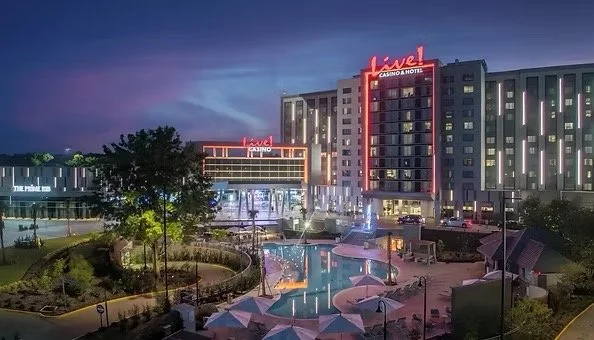 Nighttime view of the Luxel Casino & Hotel, with illuminated signage and a lit recreational pool area in the foreground.