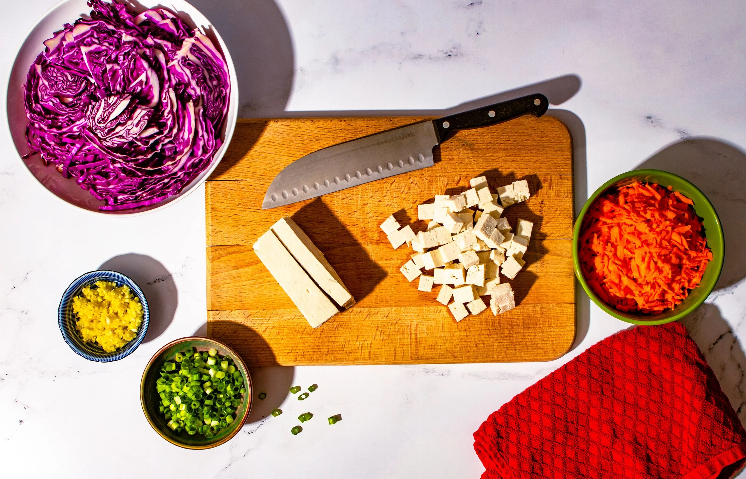 food photography chef's knife on wooden cutting board with colorful veggies prepped in bowls