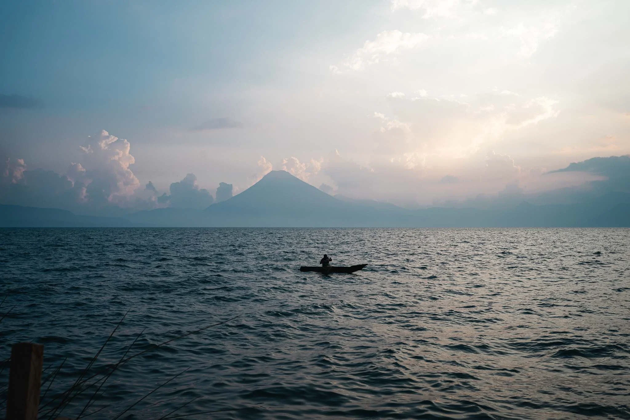 Lone fisherman on Lake Atitlan at sunset with volcano in the background