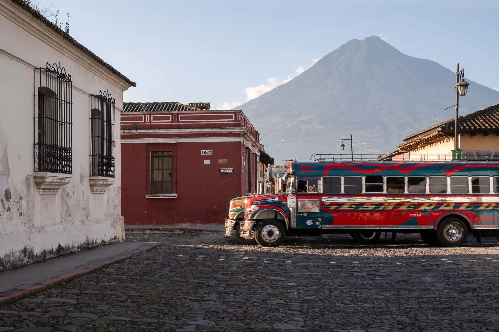 Famous, colorful chicken bus in the streets of Antigua with Volcano Agua in the background