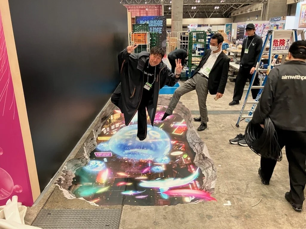 Visitors step onto a 3D illusion floor at a trade show booth