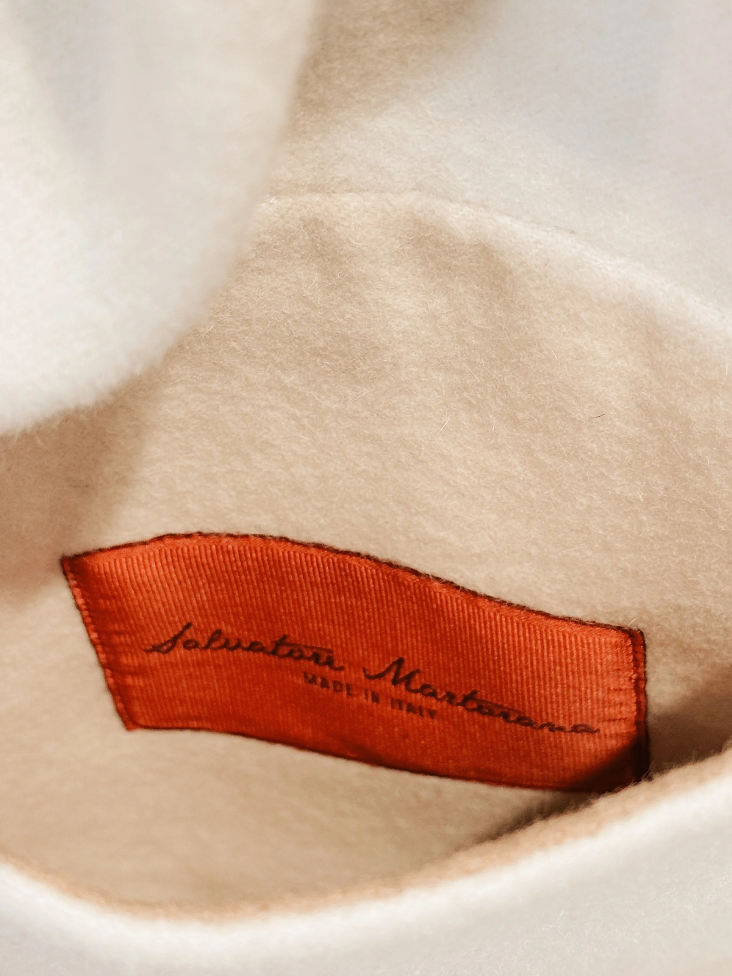 Close-up of a white fabric with a red tag reading 'Salvatore M...' and 'Made in Italy' stitched onto it.