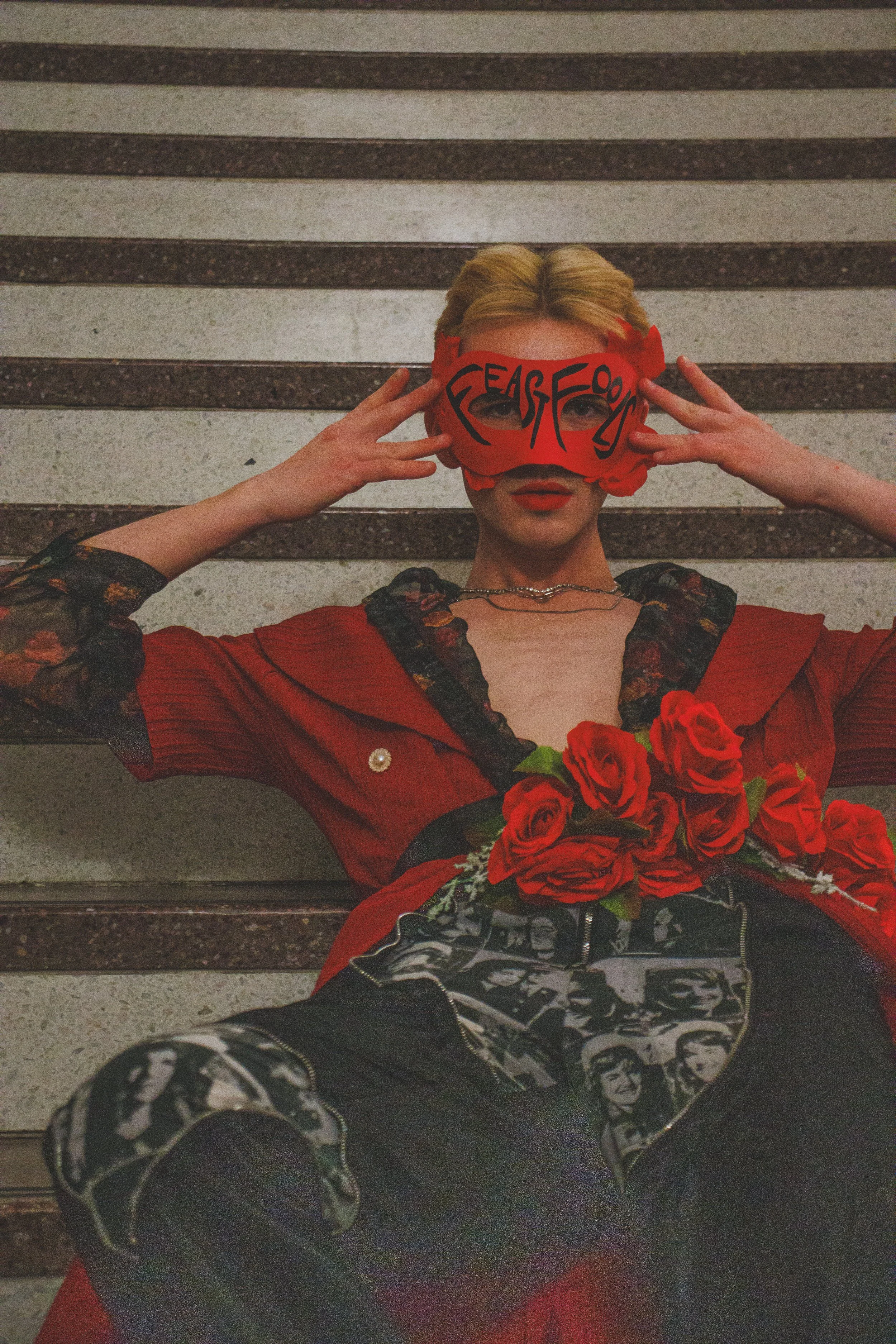 Person in a red costume and face mask holding red roses in front of wooden steps