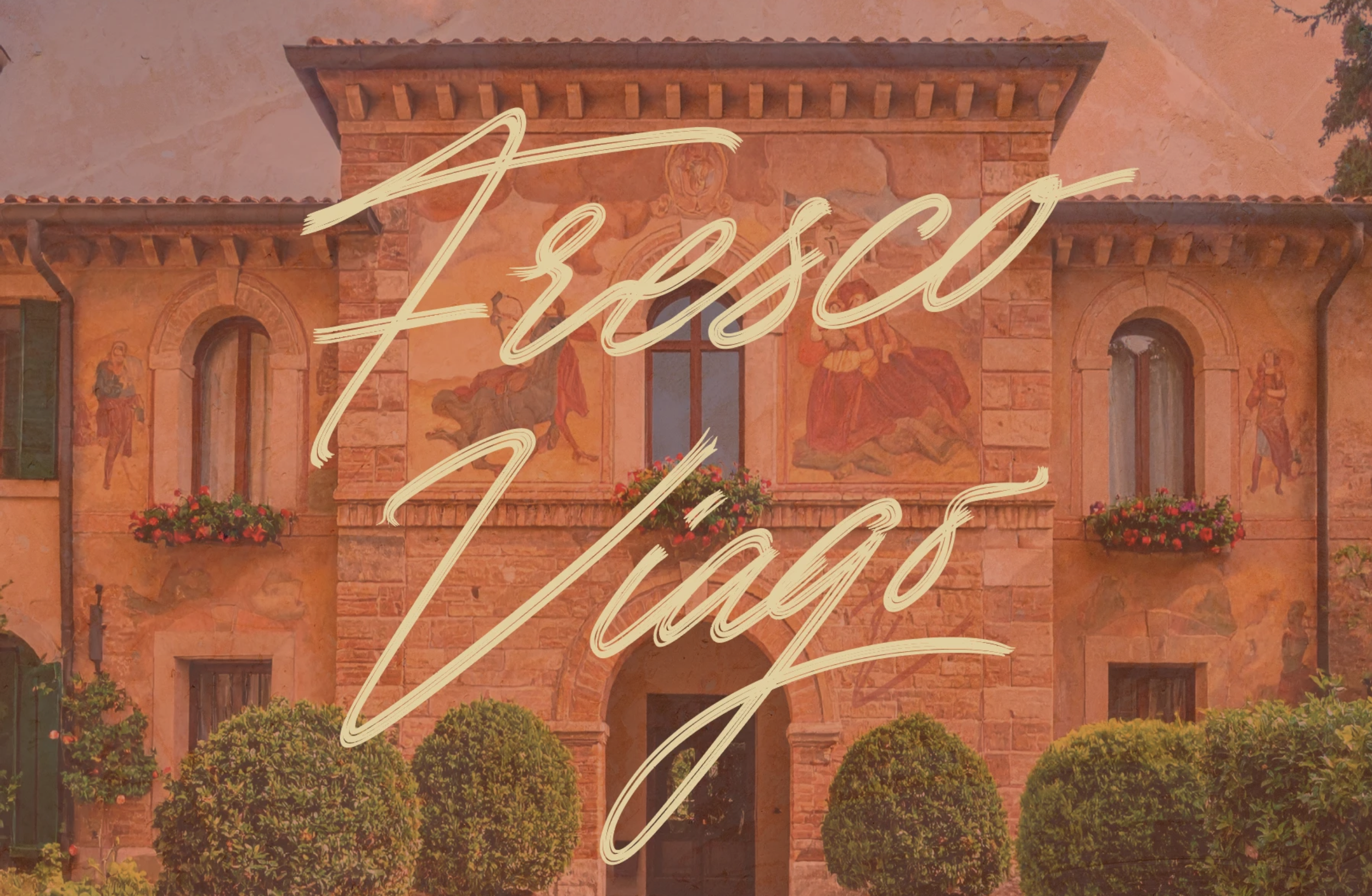 Historic Spanish mission-style building with painted religious murals, arched doorways, flower boxes, manicured shrubs, and cream brush lettering overlay