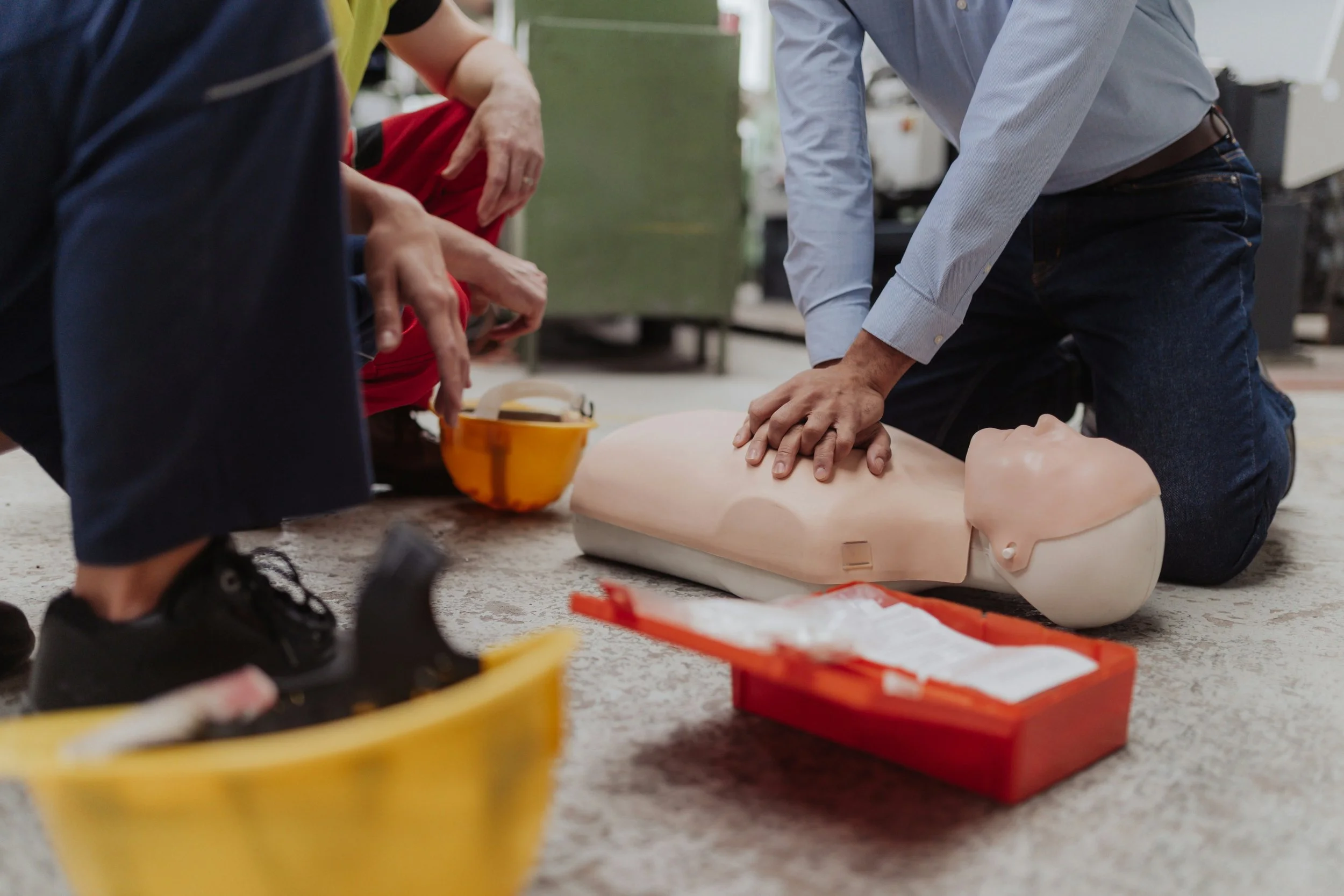 People practicing CPR on a training mannequin in a classroom or training environment.