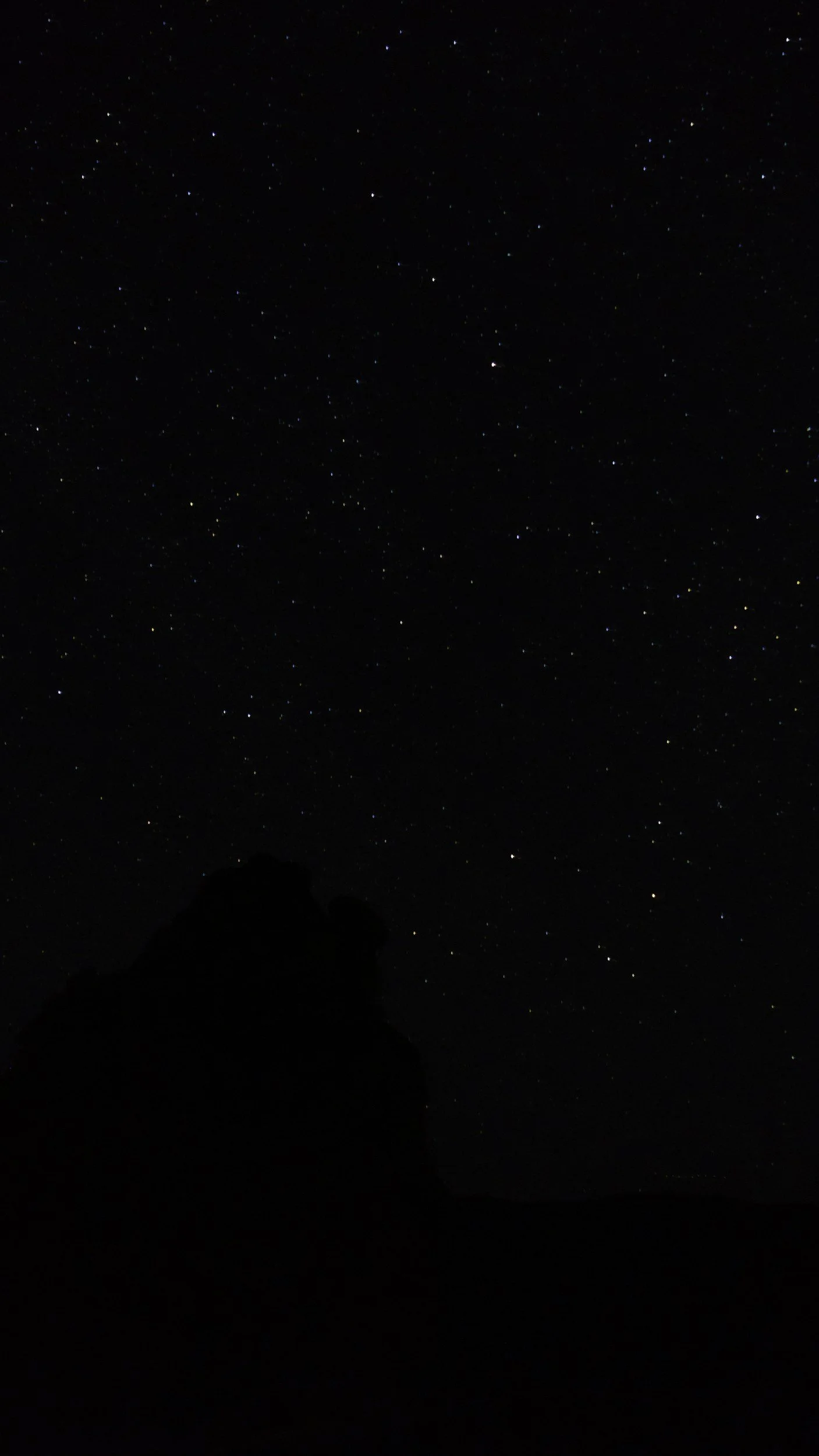 A night sky filled with numerous visible stars and a few faint planets or celestial bodies.