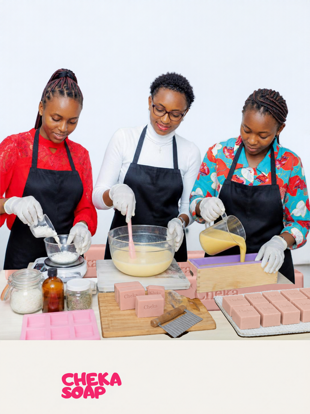Three women making soap together, wearing aprons and gloves, with soap molds, ingredients, and tools on the table.