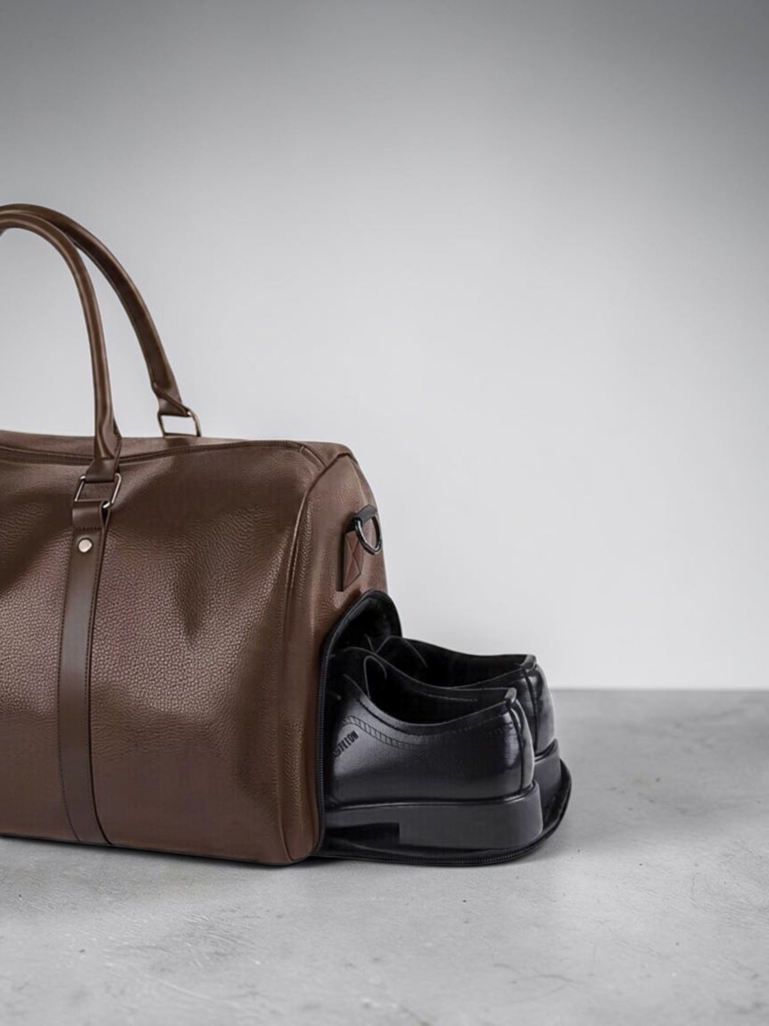 NORETI Ravelle espresso brown vegan leather duffle bag showing dedicated side shoe compartment with black leather shoes.