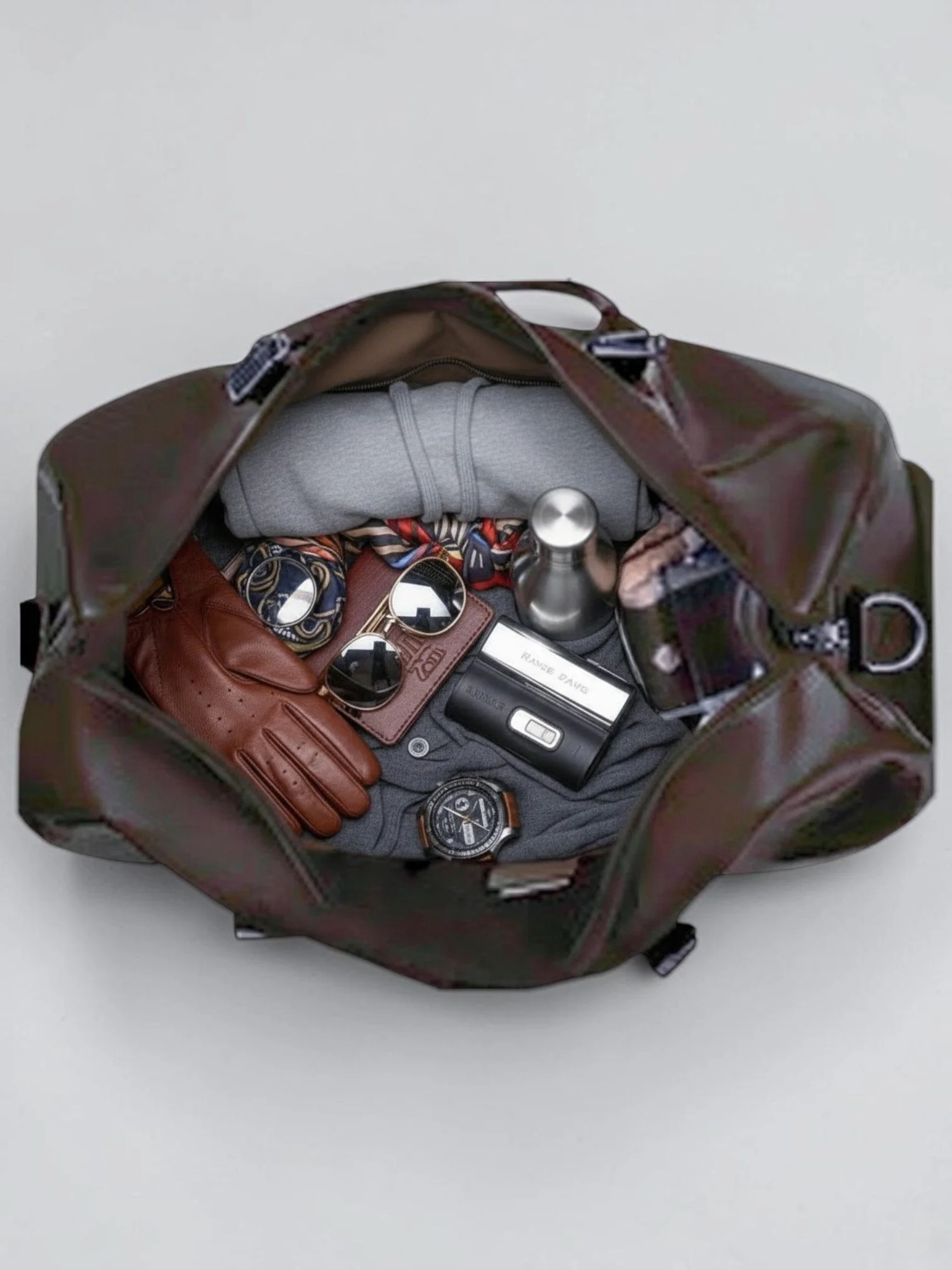 NORETI Ravelle espresso brown weekender bag with open main compartment displaying clothing, watches and travel essentials.