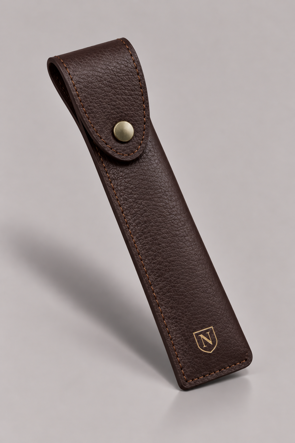 NORETI Varen brown leather pouch showing pebbled grain, curved snap flap and stitched edging.