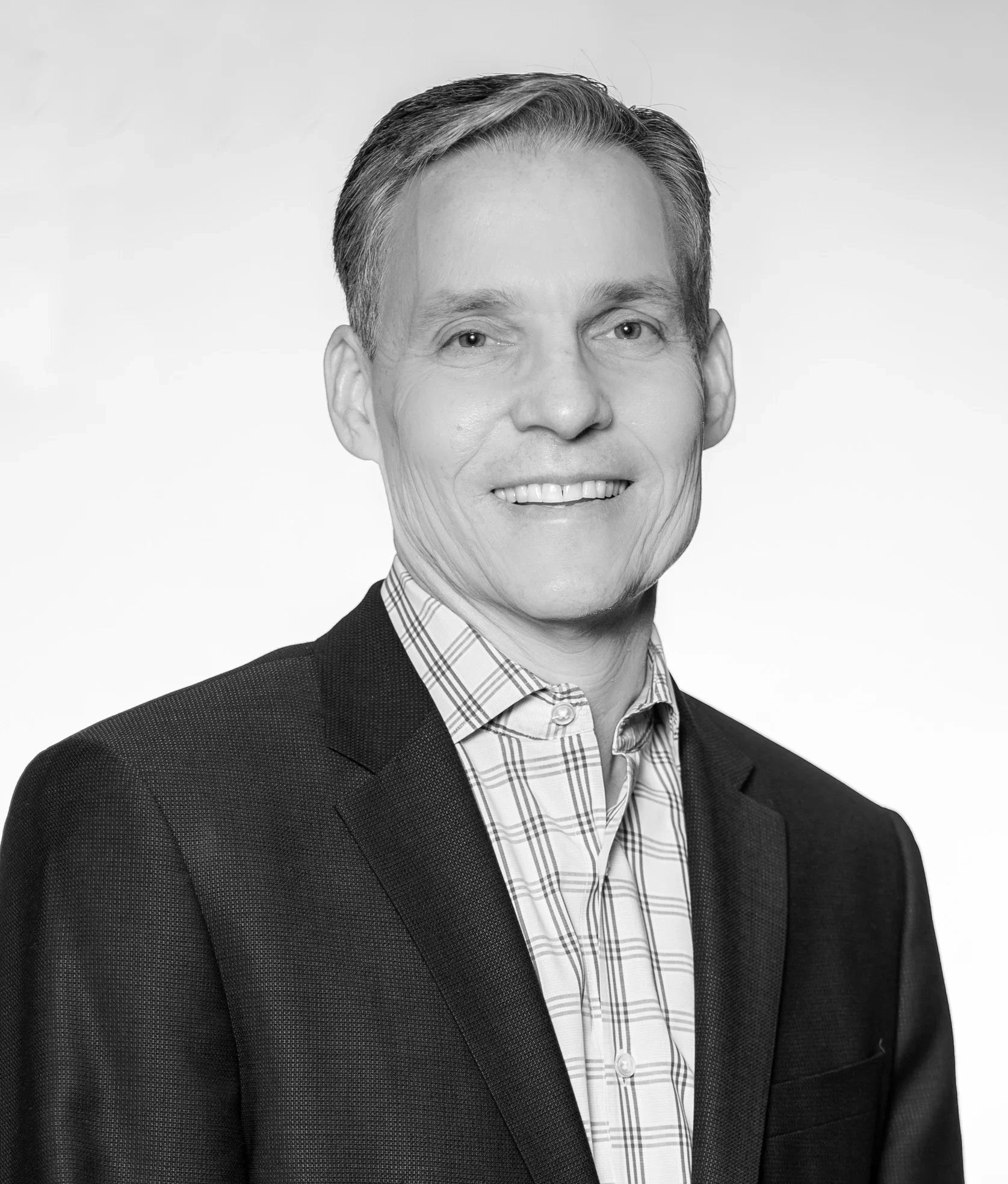 Black-and-white portrait of Rob Benson in a suit and a checked shirt, turned slightly to the right.