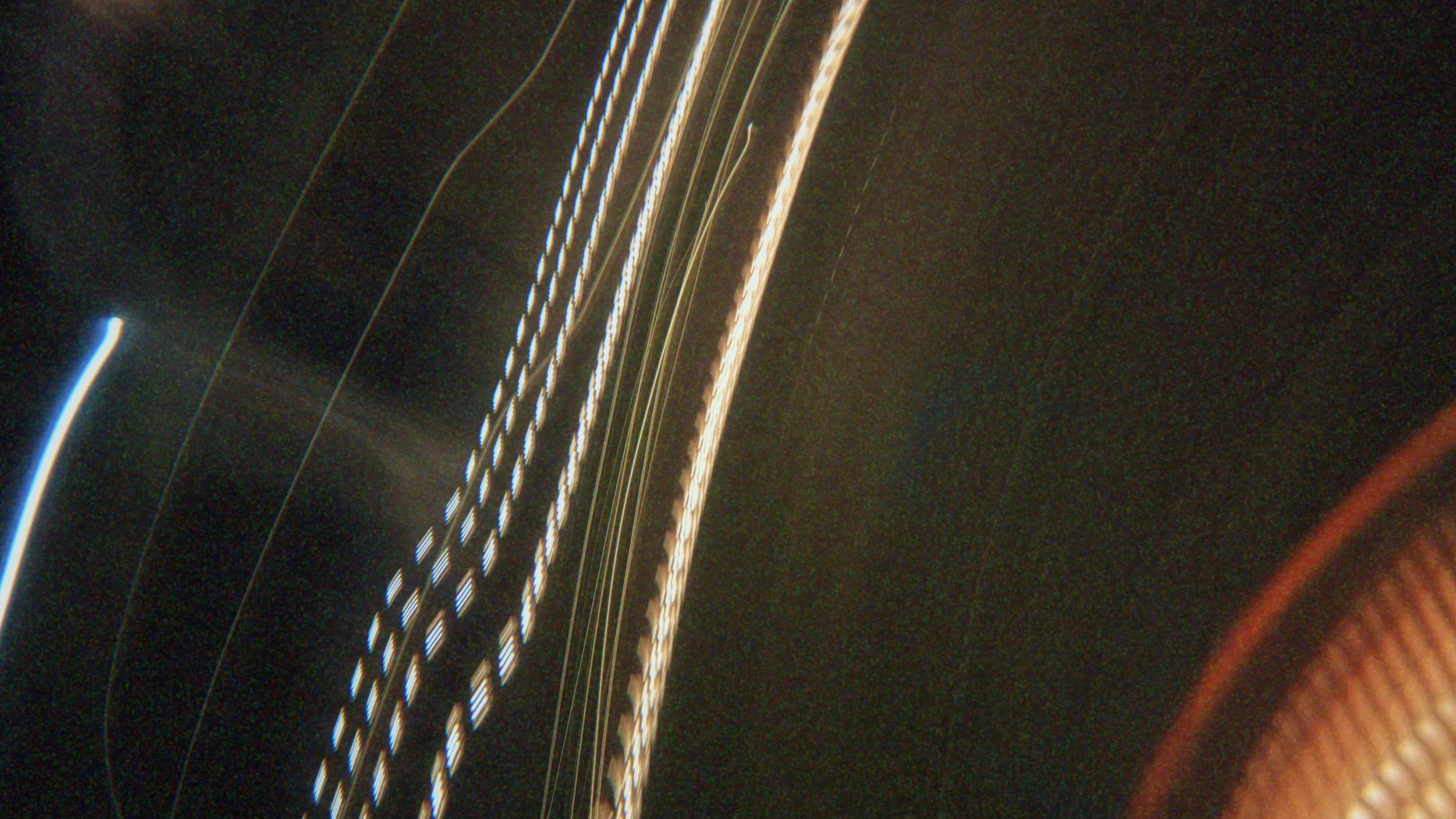 Close-up of illuminated lines and patterns on a dark surface, possibly a electronic device or decorative material, with some orange and red rounded edges.