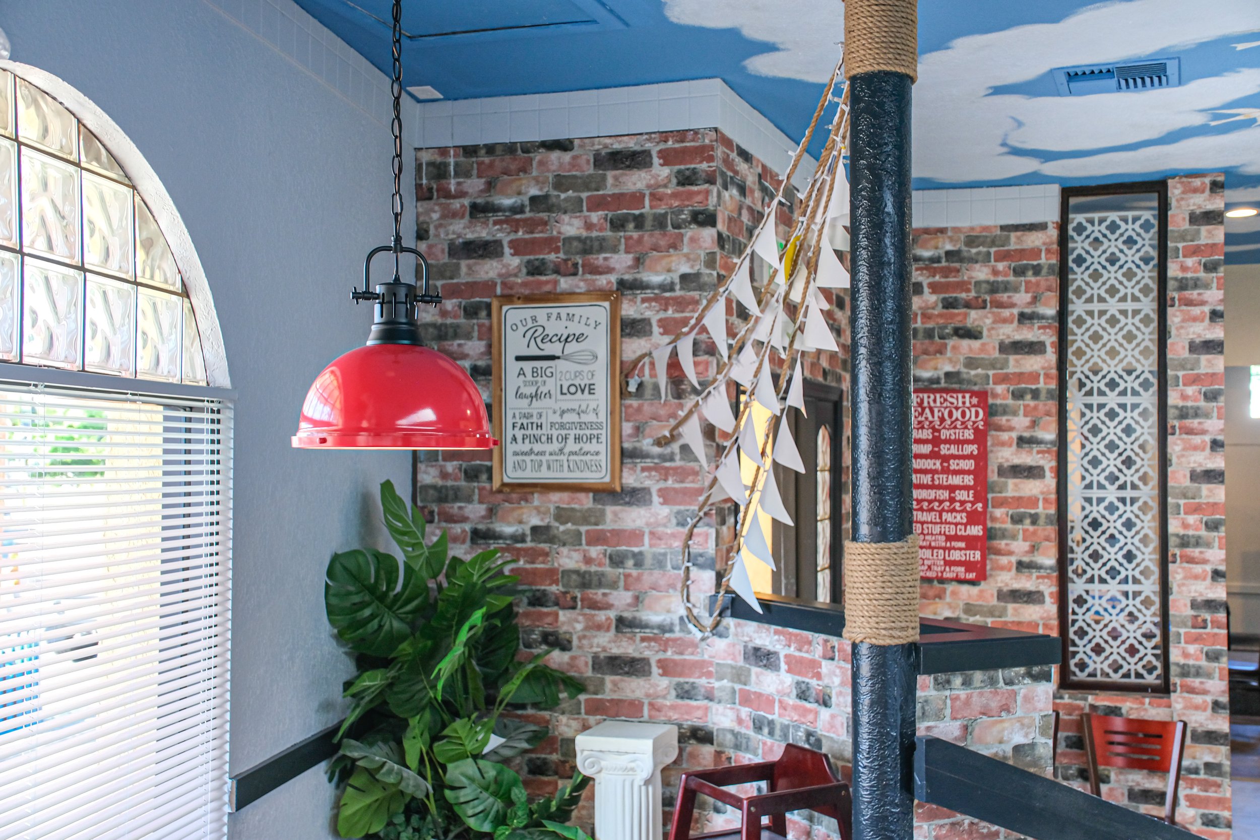 Interior of Crawfish & Hotspot restaurant featuring exposed brick walls, nautical-inspired decor, tropical plants, and a welcoming dining area.